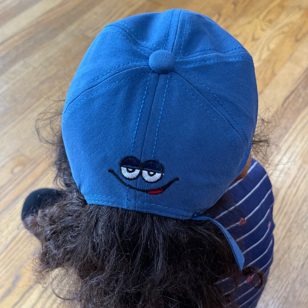 Kids baseball cap in bright blue with a cartoon “m” character patch