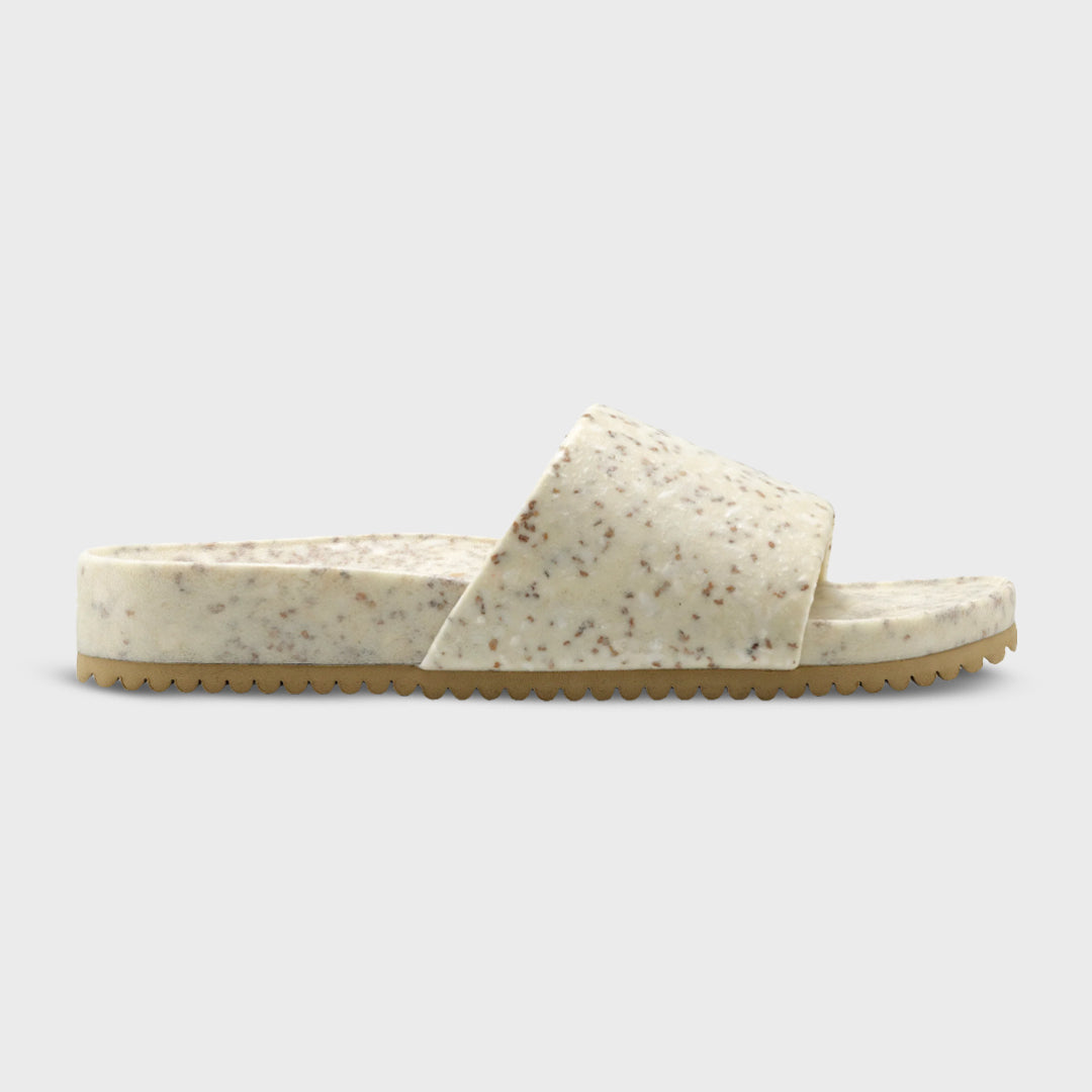 Speckled slide sandal with wide band upper and ridged tan sole, side profile.