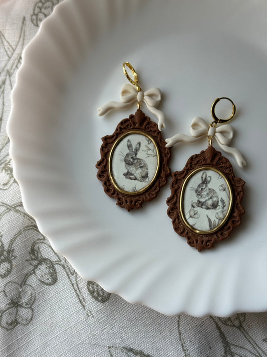 Vintage rabbit oval frame drop earrings, ornate brown border, white flower, gold hooks