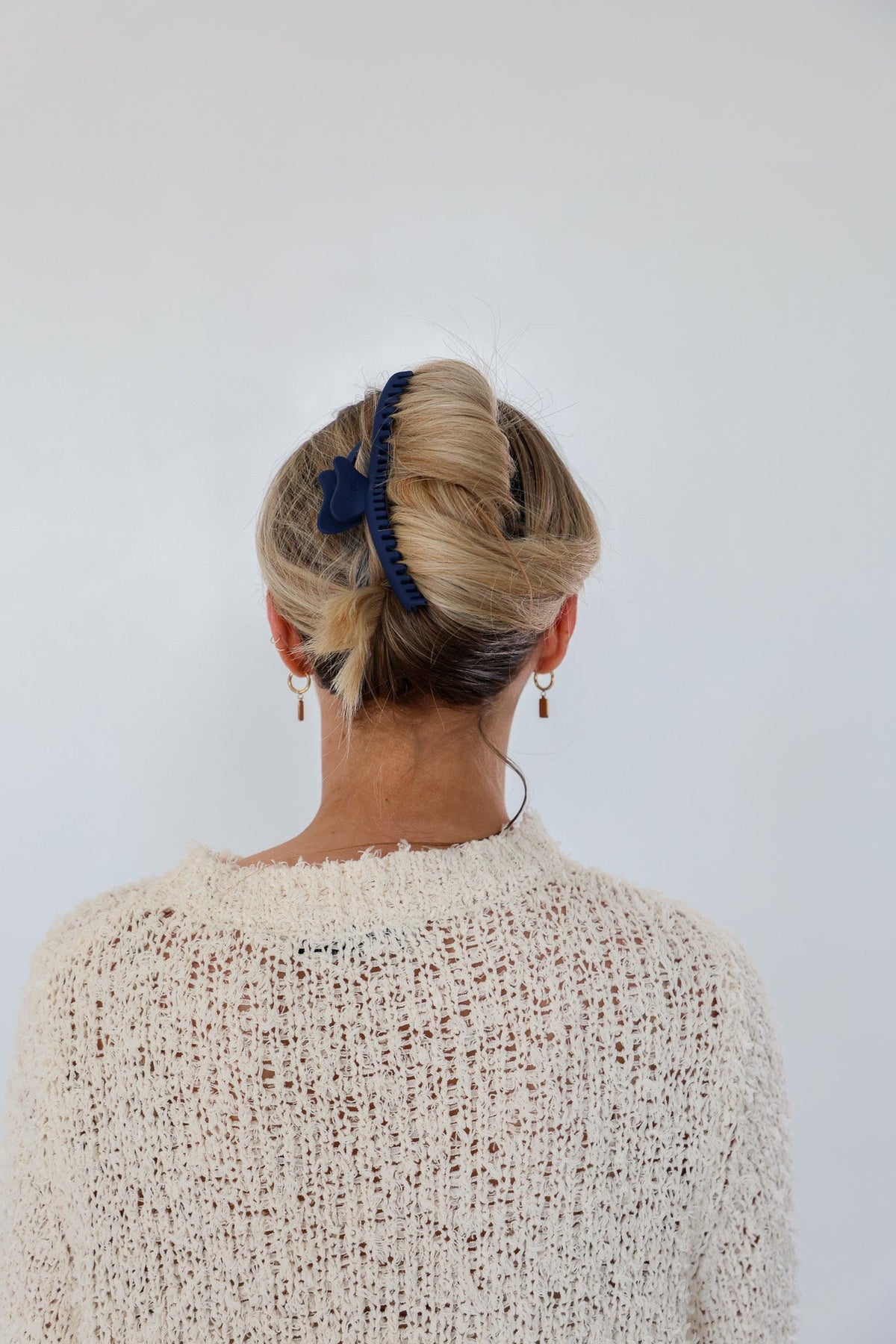 Dark blue wavy hair claw holding blonde hair up from behind