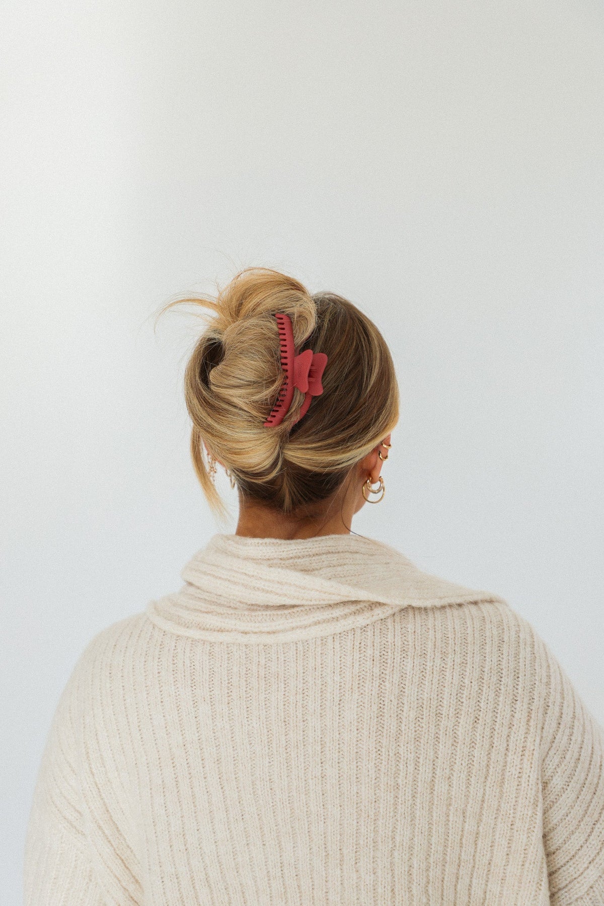 Wavy midi claw hair clip holding a bun, light-colored hair, pink clip