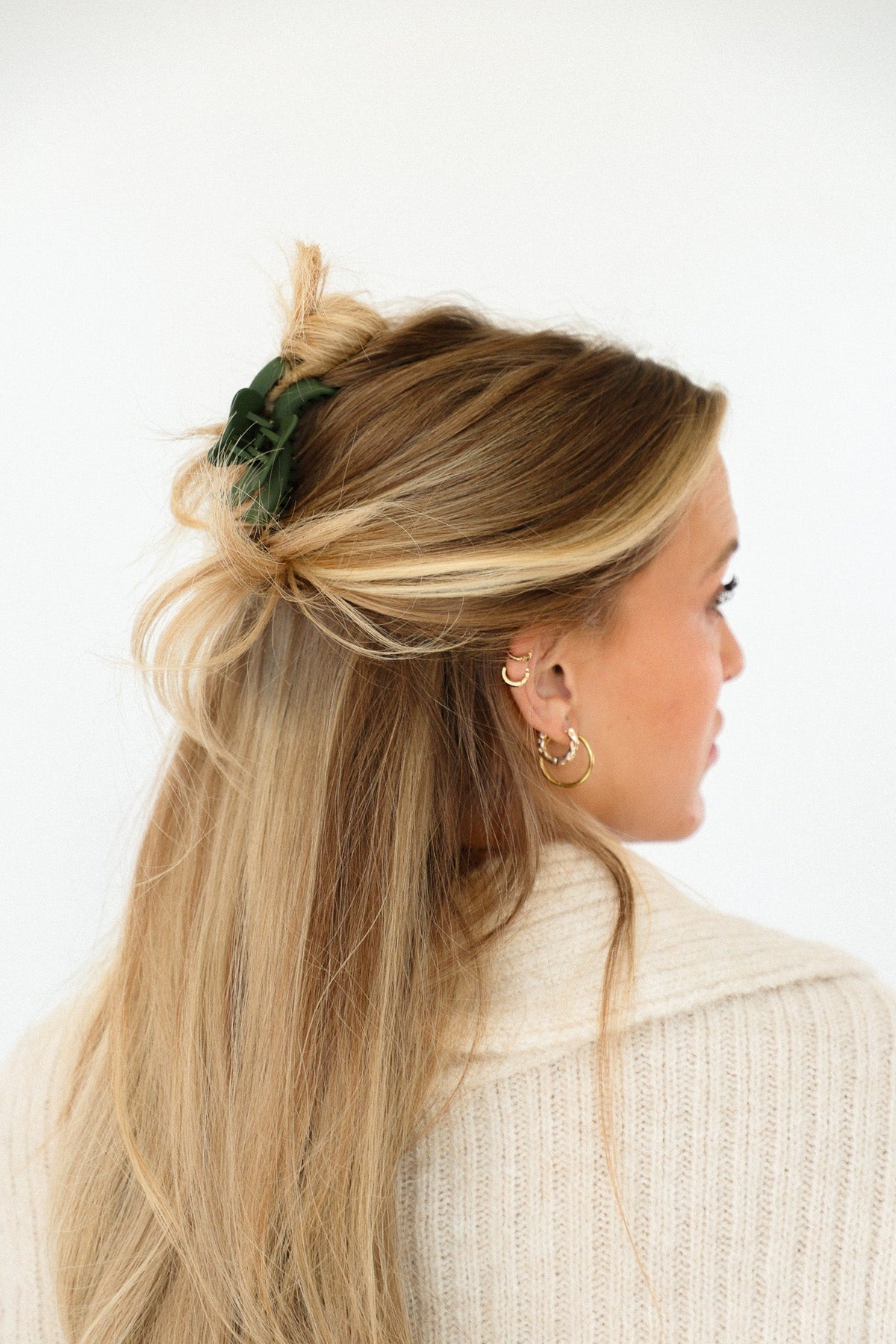 Green wavy mini claw hair clip holding blonde ponytail