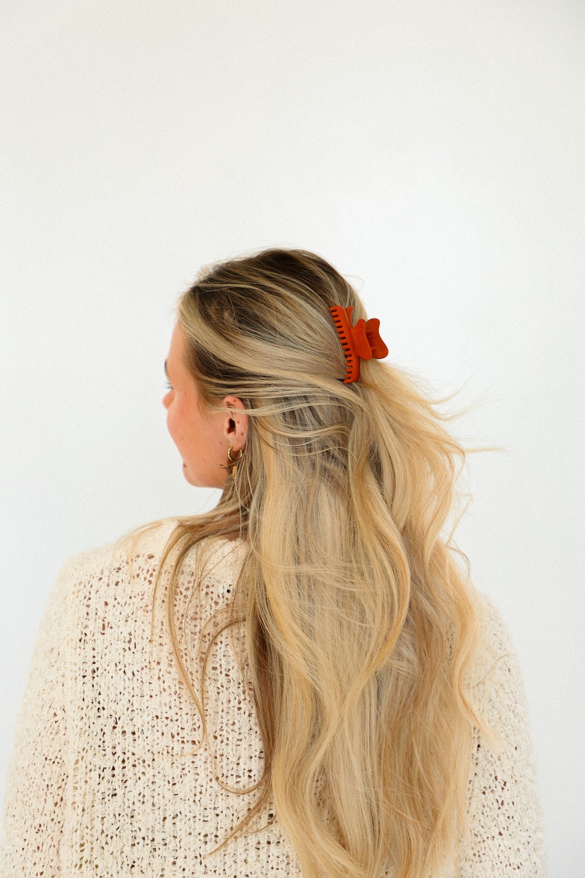 Orange mini claw hair clip on blonde hair bun from side
