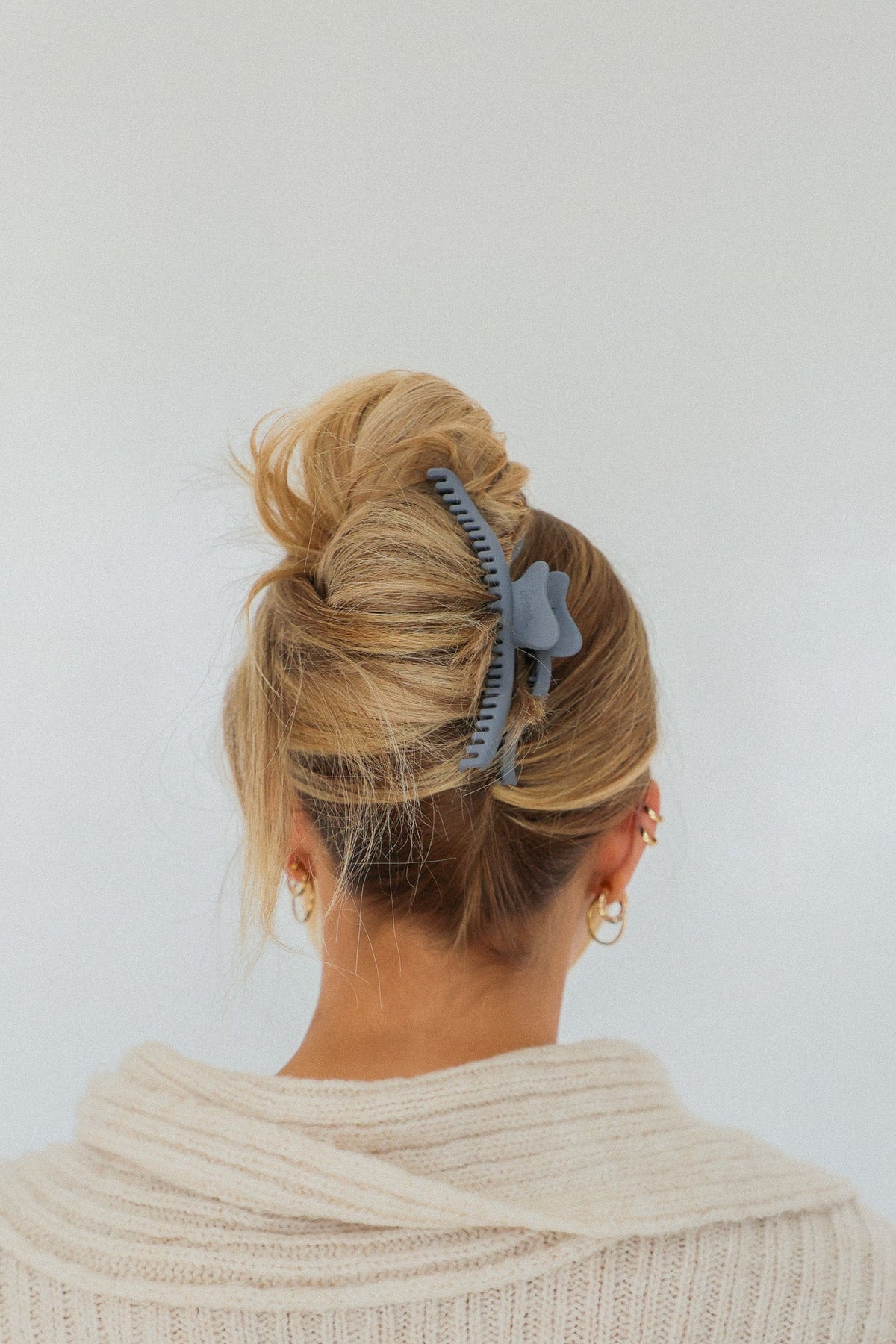 Wavy claw hair clip in light blue holding a low bun