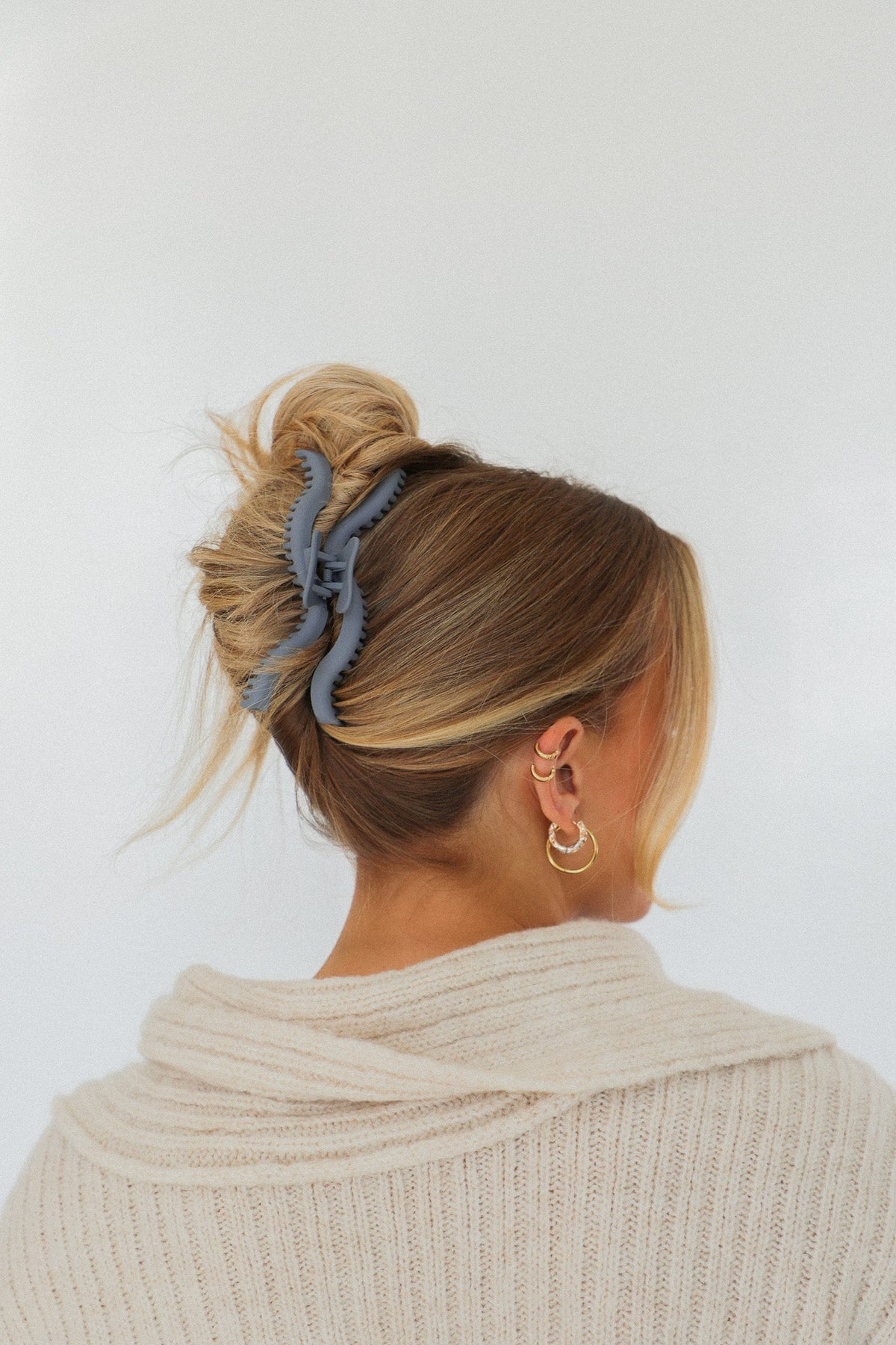 Wavy claw hair clip in dusty blue holding a bun on blonde hair
