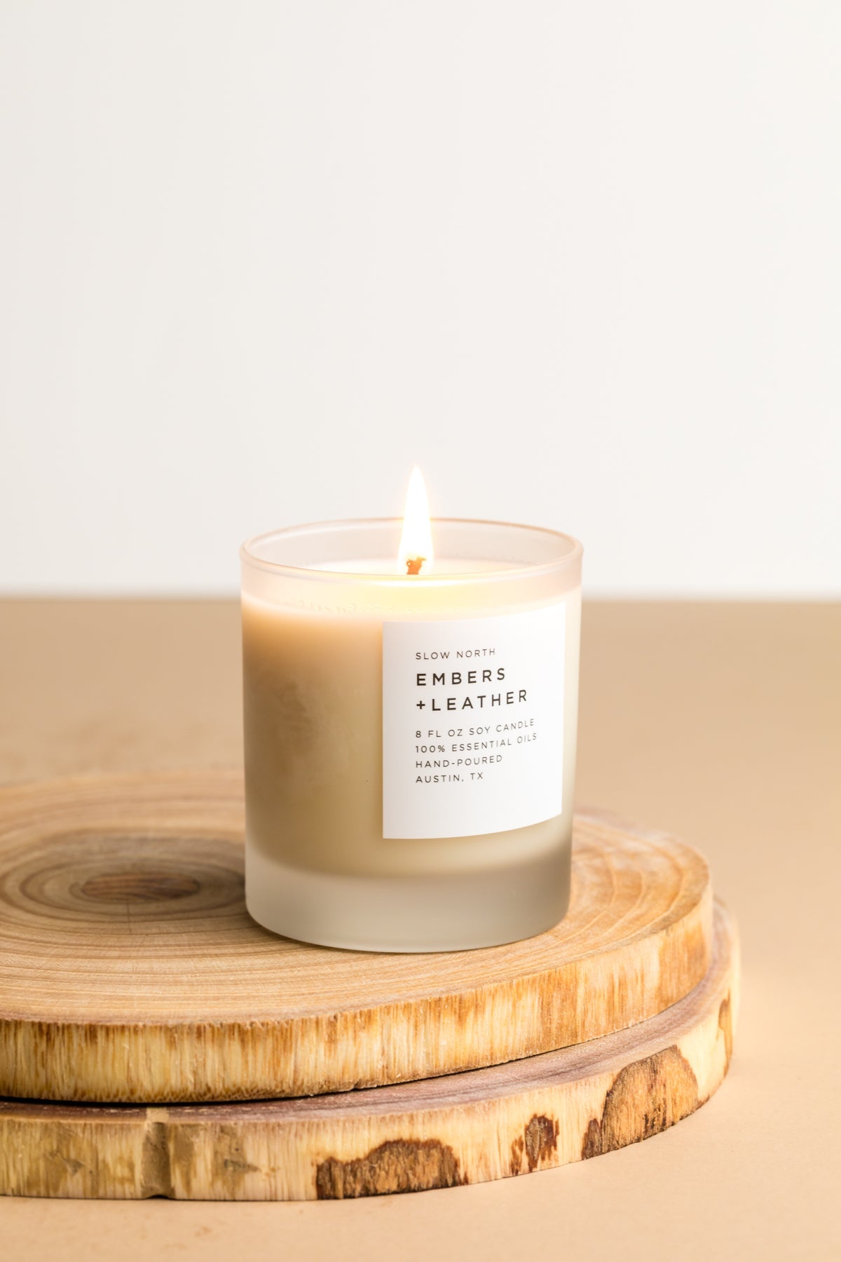 Small lit Embers + Leather candle in a frosted glass jar.