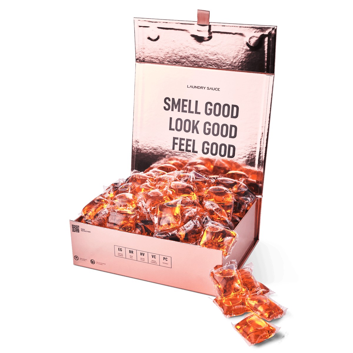 Laundry detergent pod box open with orange gel pods; one pod in front