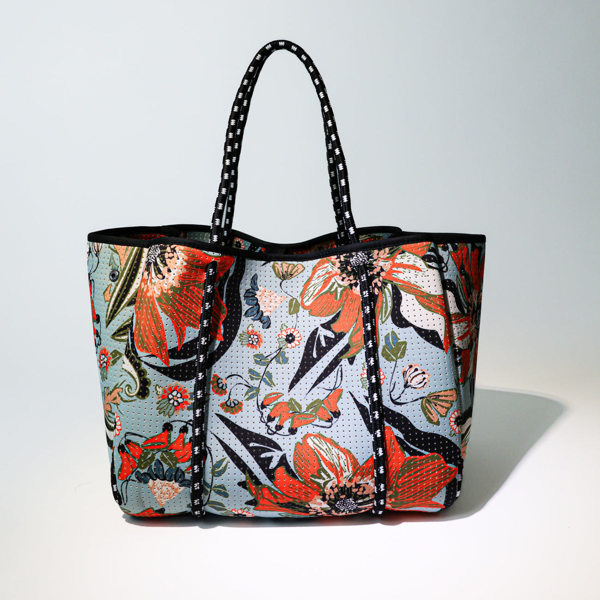 Colorful floral patterned tote bag with black handles and reinforced front panel