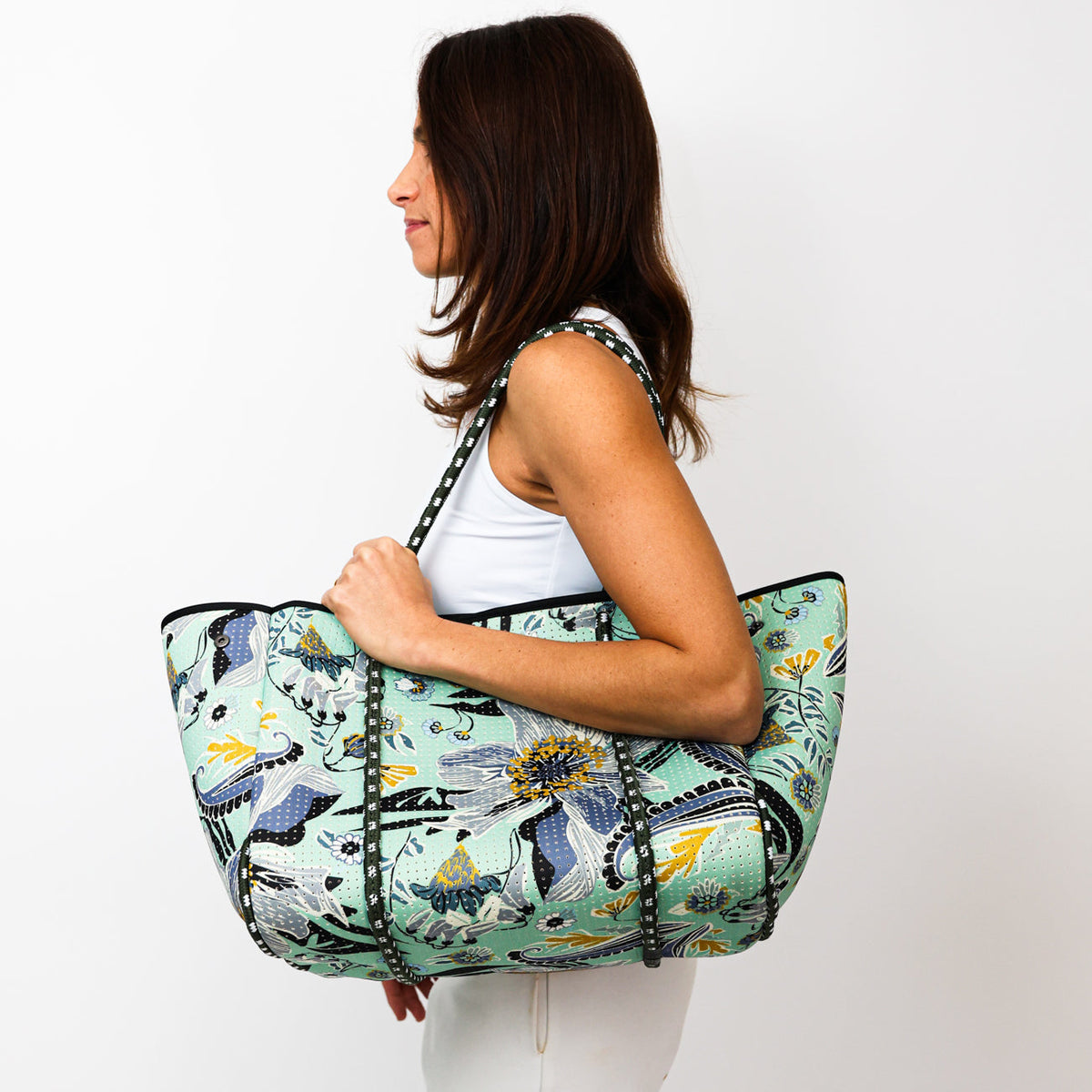 Mint patterned tote bag with black trim and long handles, held over shoulder