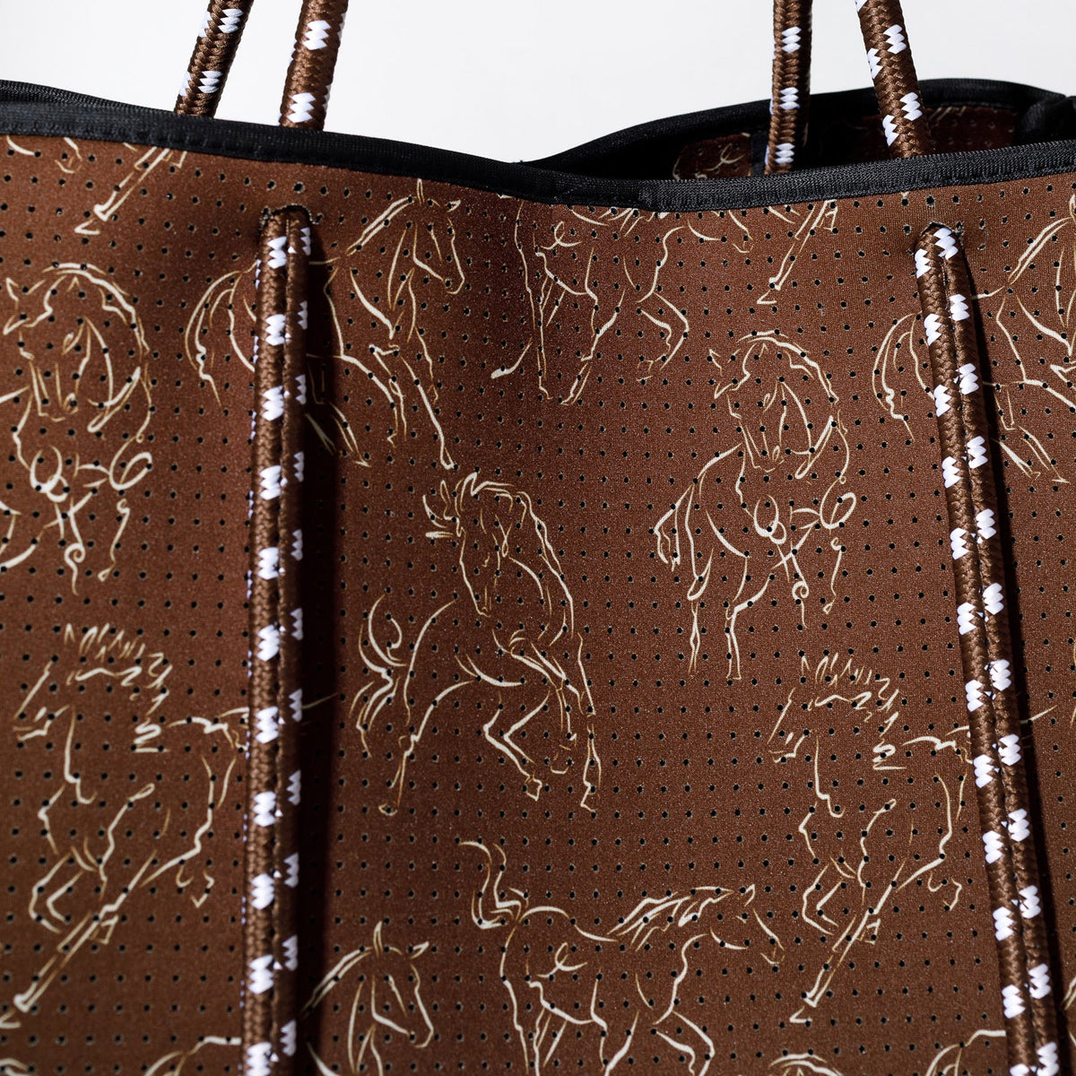 Horse-print tote fabric detail with perforated texture and striped braided trim