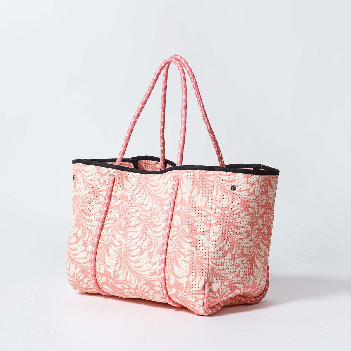 Pink palm-leaf tote bag with black top band and pink rope handles, side view
