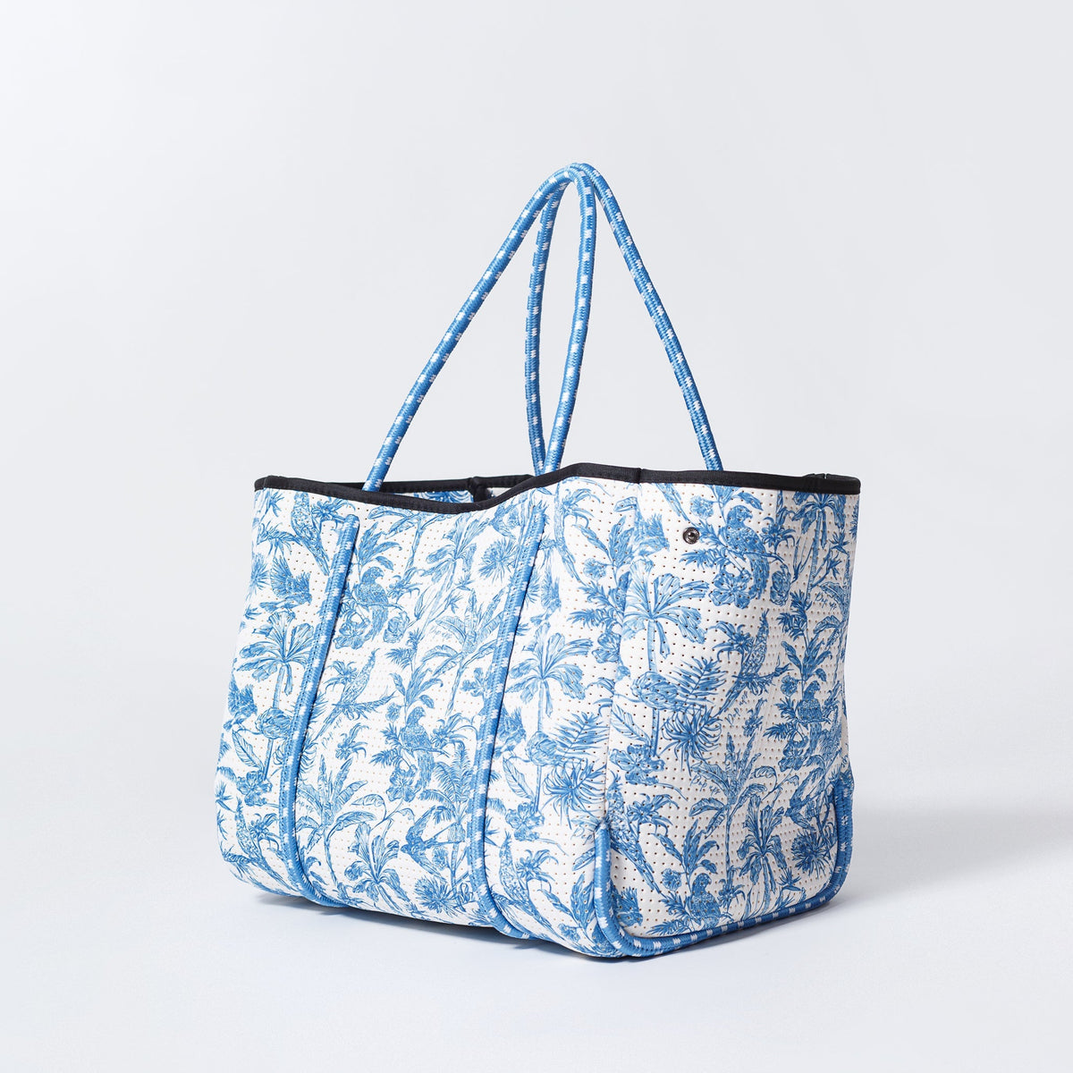 Blue and white tropical print tote bag with black top trim and blue handles