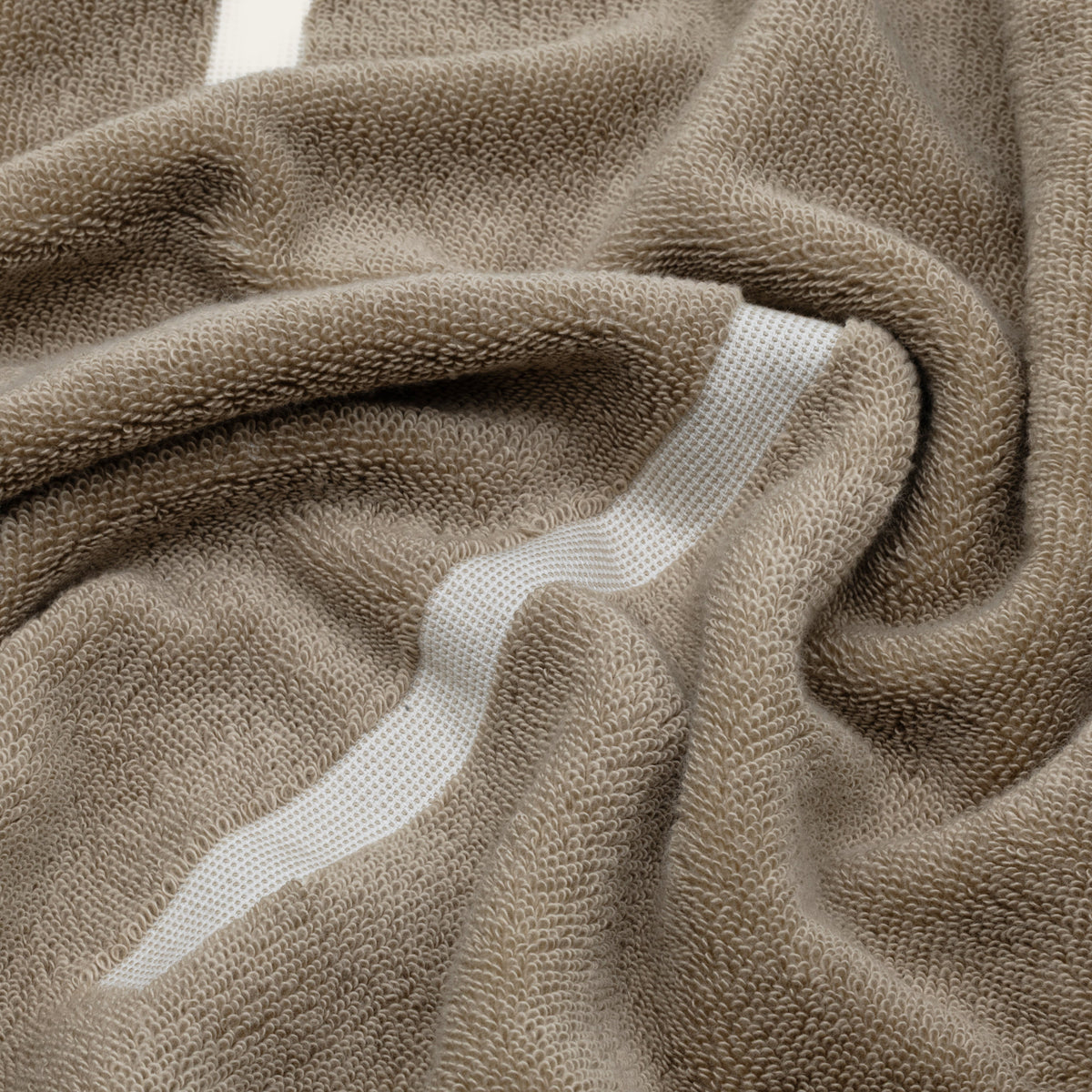 Close-up of tan and ecru cotton towel with white stripe accents and loops