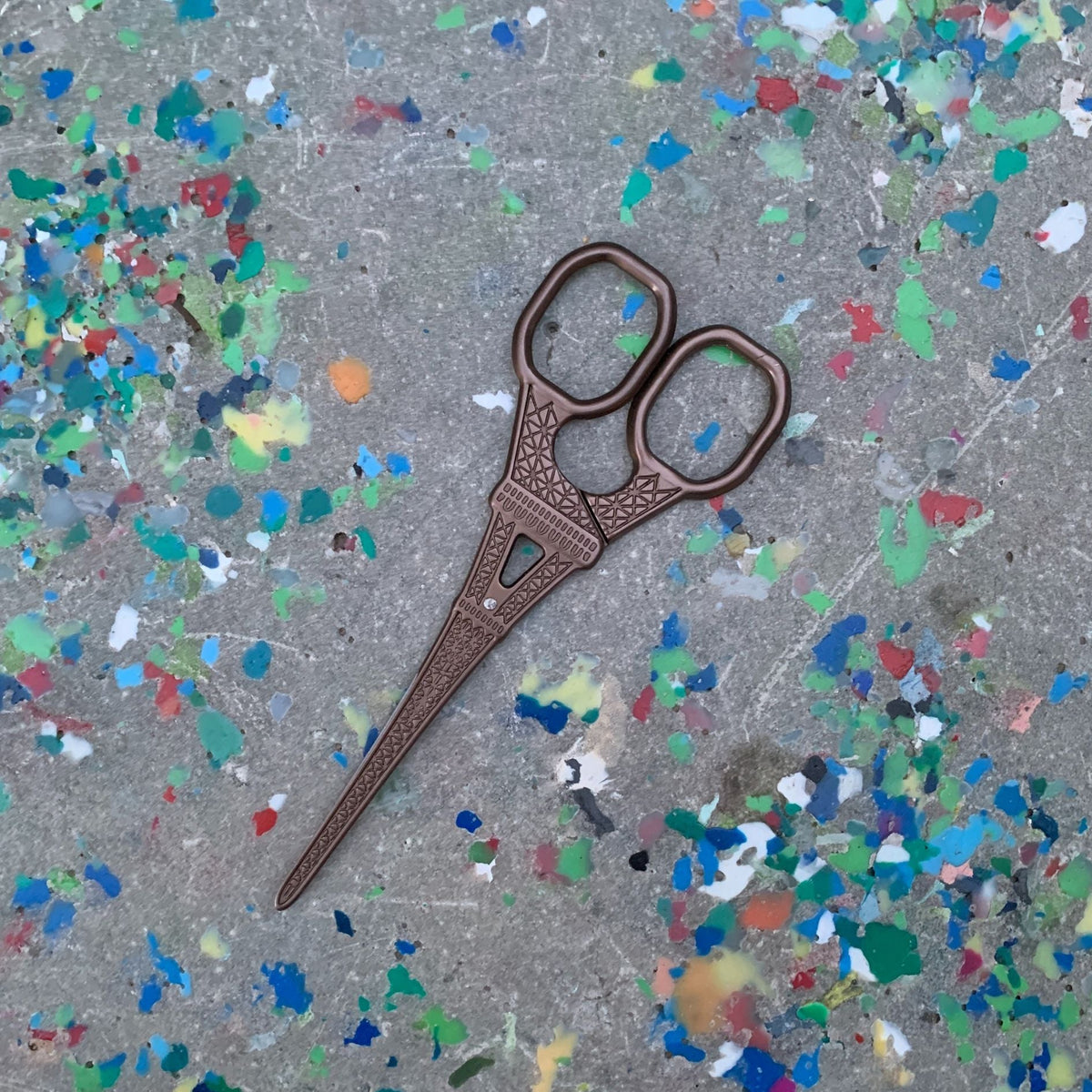 Eiffel Tower mini scissors, bronze finish with small blue inlay, angled view, two loops.