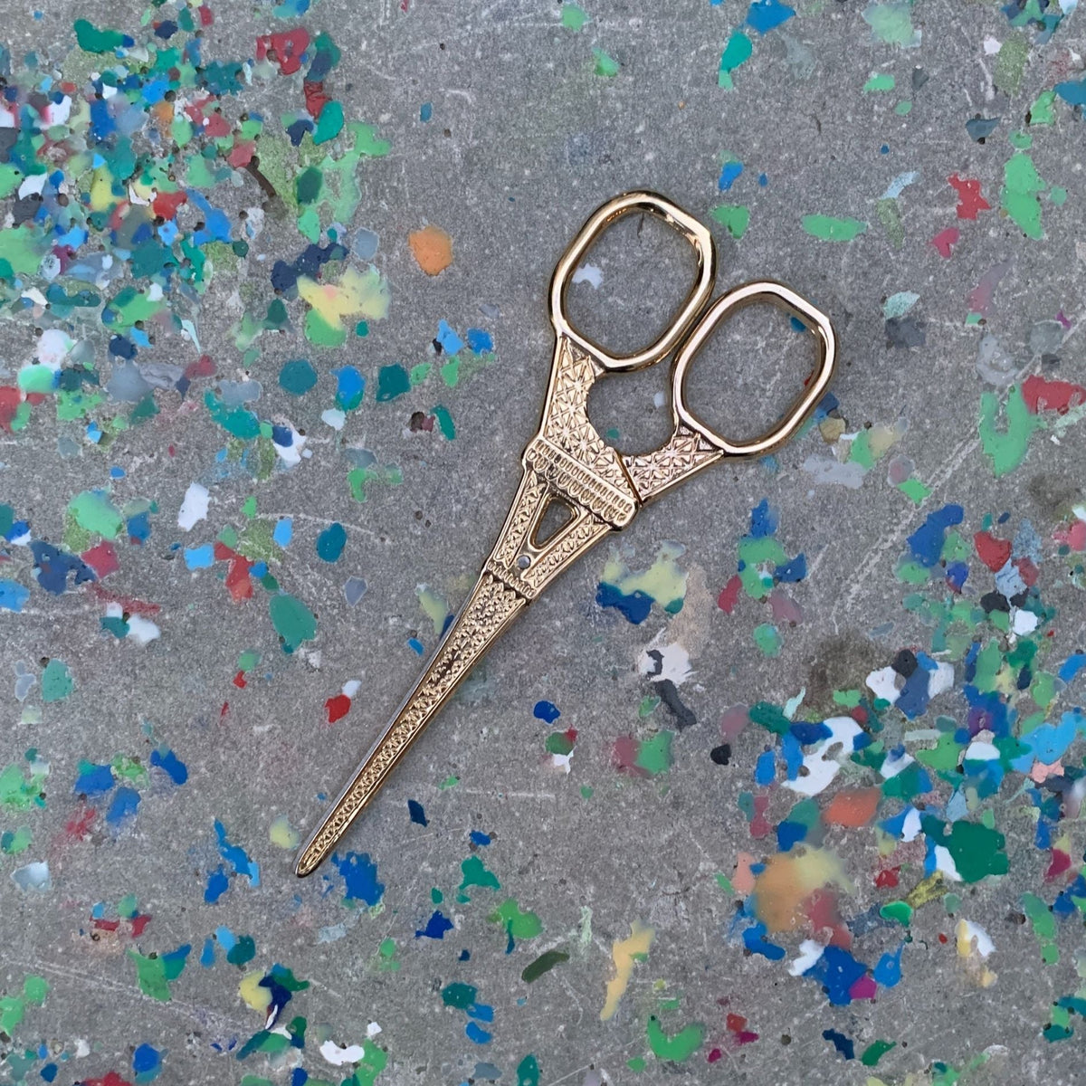 Eiffel Tower mini scissors, light gold tone with textured details, two finger loops, close-up.
