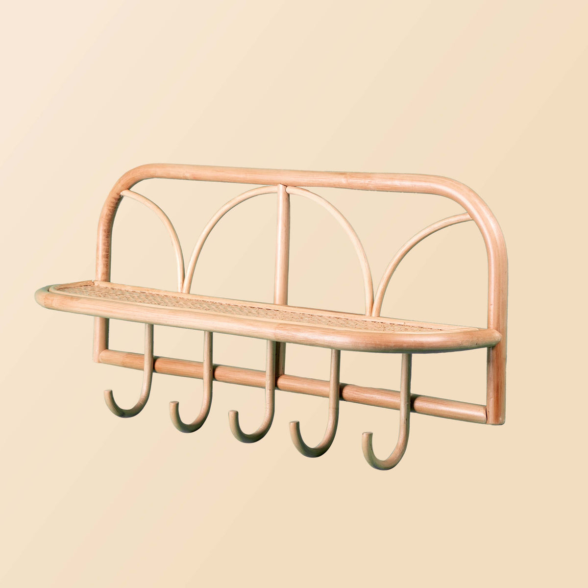 Angled view of a rattan wall shelf with a woven ledge and five hooks