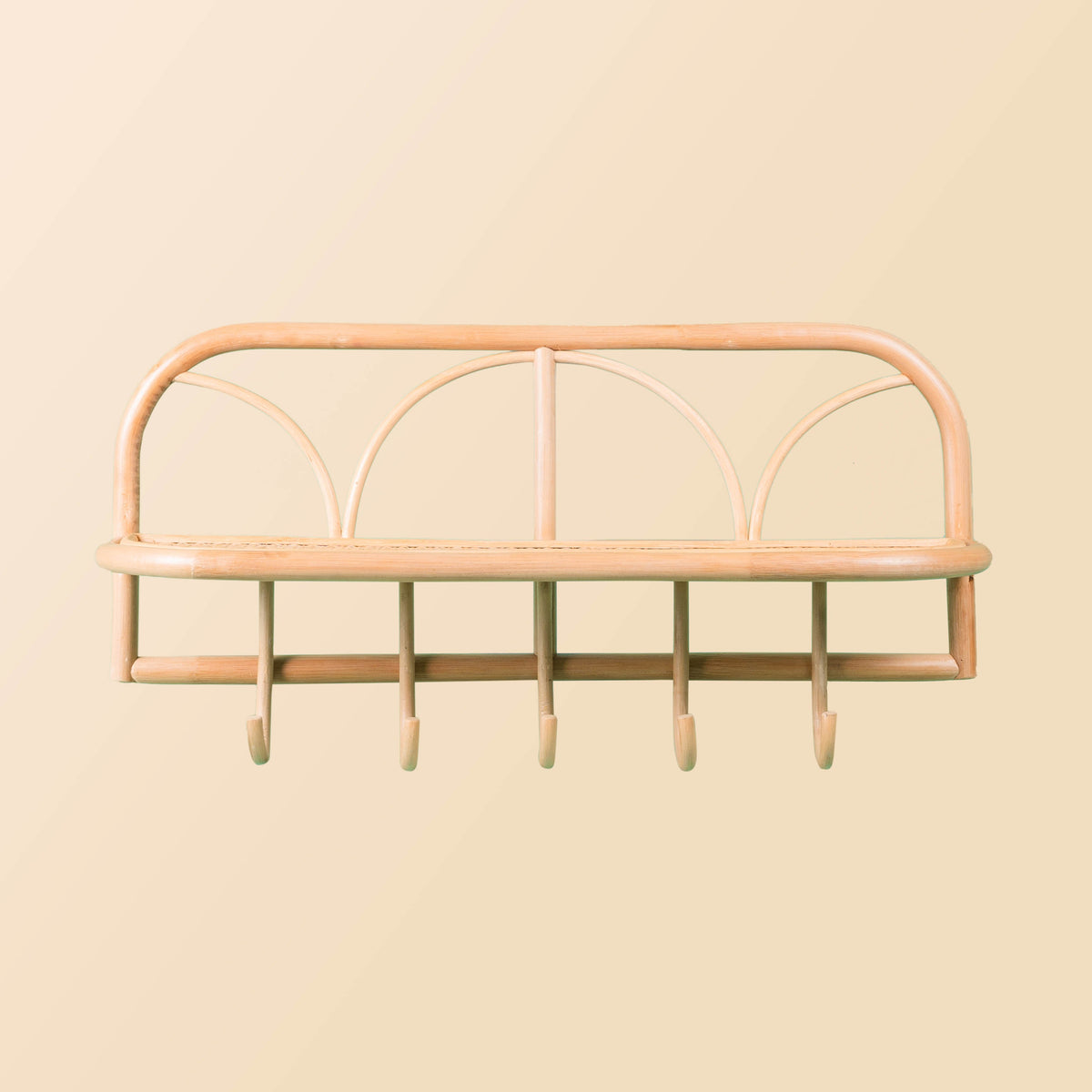 Front view of a natural rattan wall shelf with five hooks and a display ledge