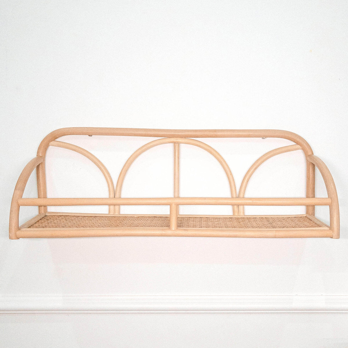 Empty rattan wall shelf with three arched dividers and woven base