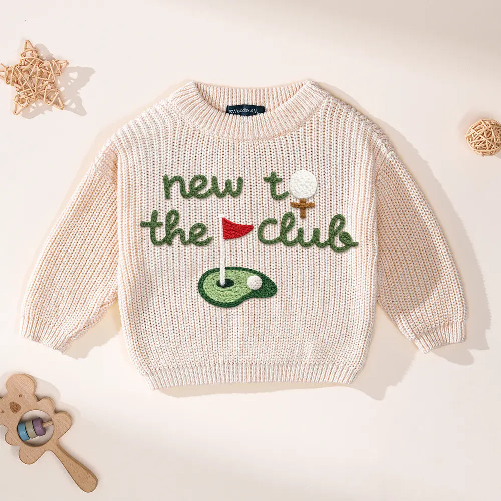 Light pink knit golf sweater with 'new to the club' embroidered golf flag design