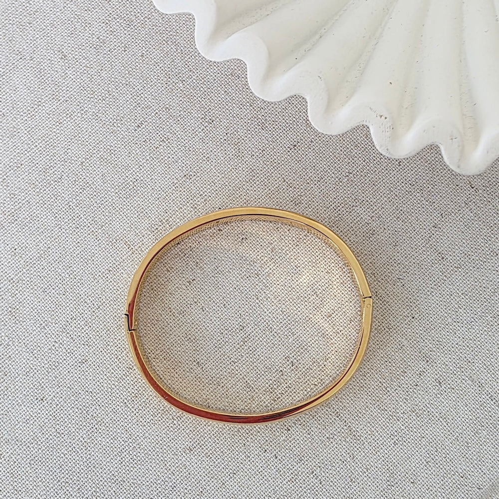 Gold-tone round hinged bangle bracelet with small clasp ends, shown flat