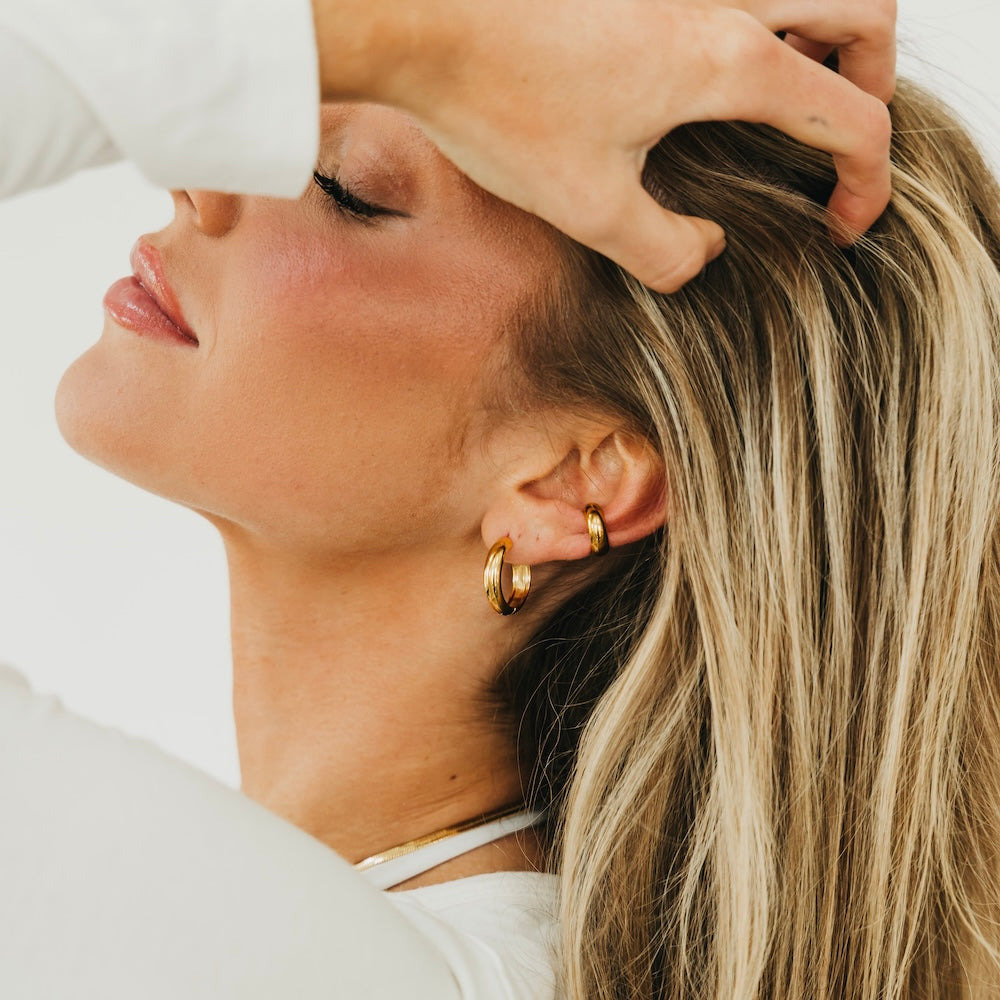 Gold hoop earrings with red enamel, close-up side profile on neck and ear