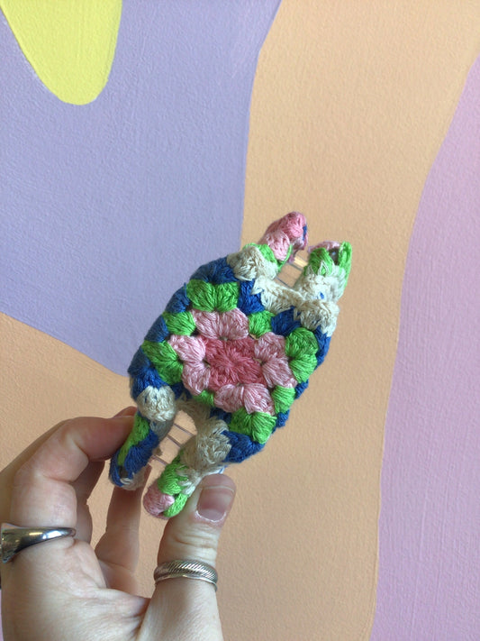Crocheted hair claw with green, blue, and pink crochet flower detail
