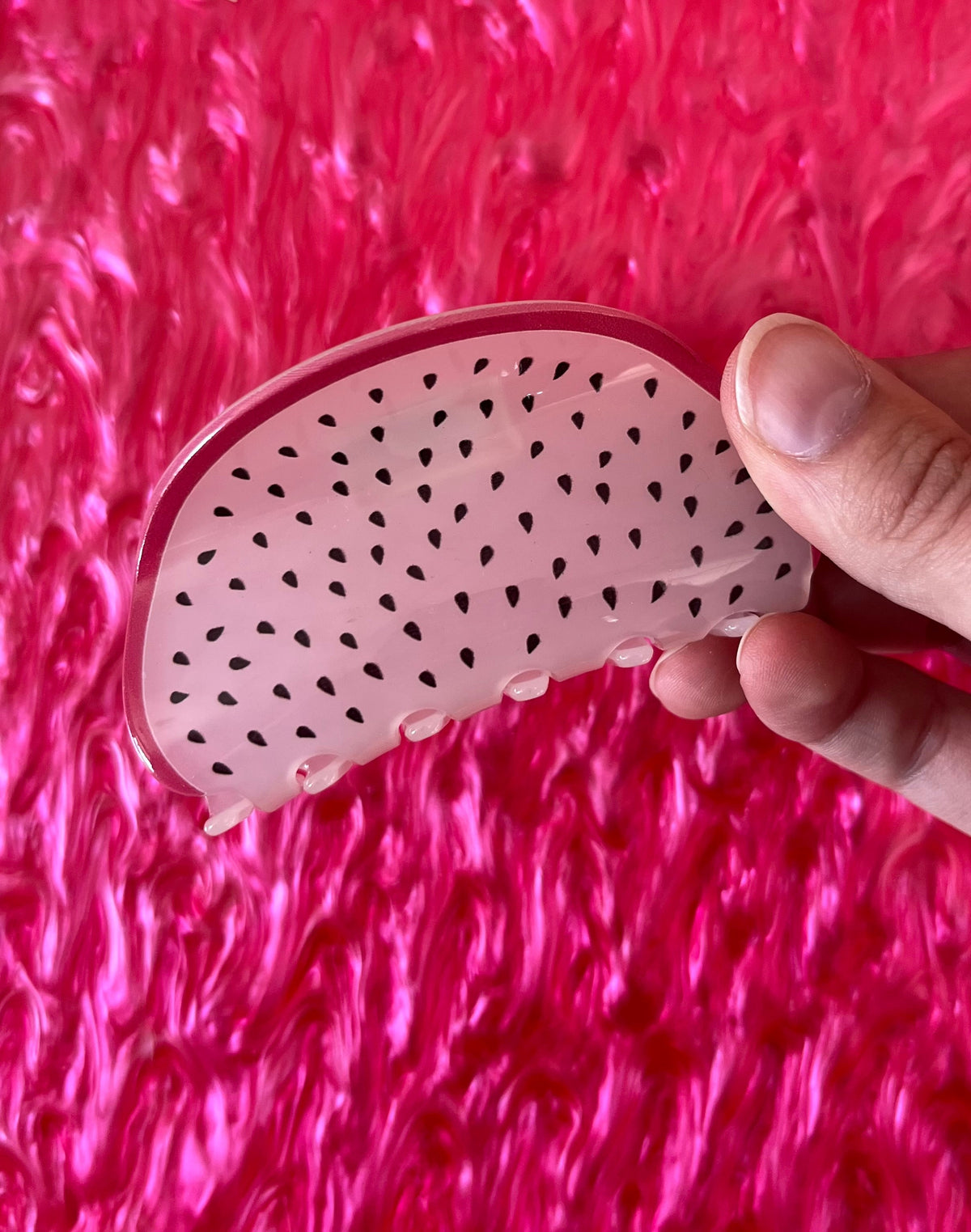 Pink fruit hair claw with black seed dots and curved snap grip