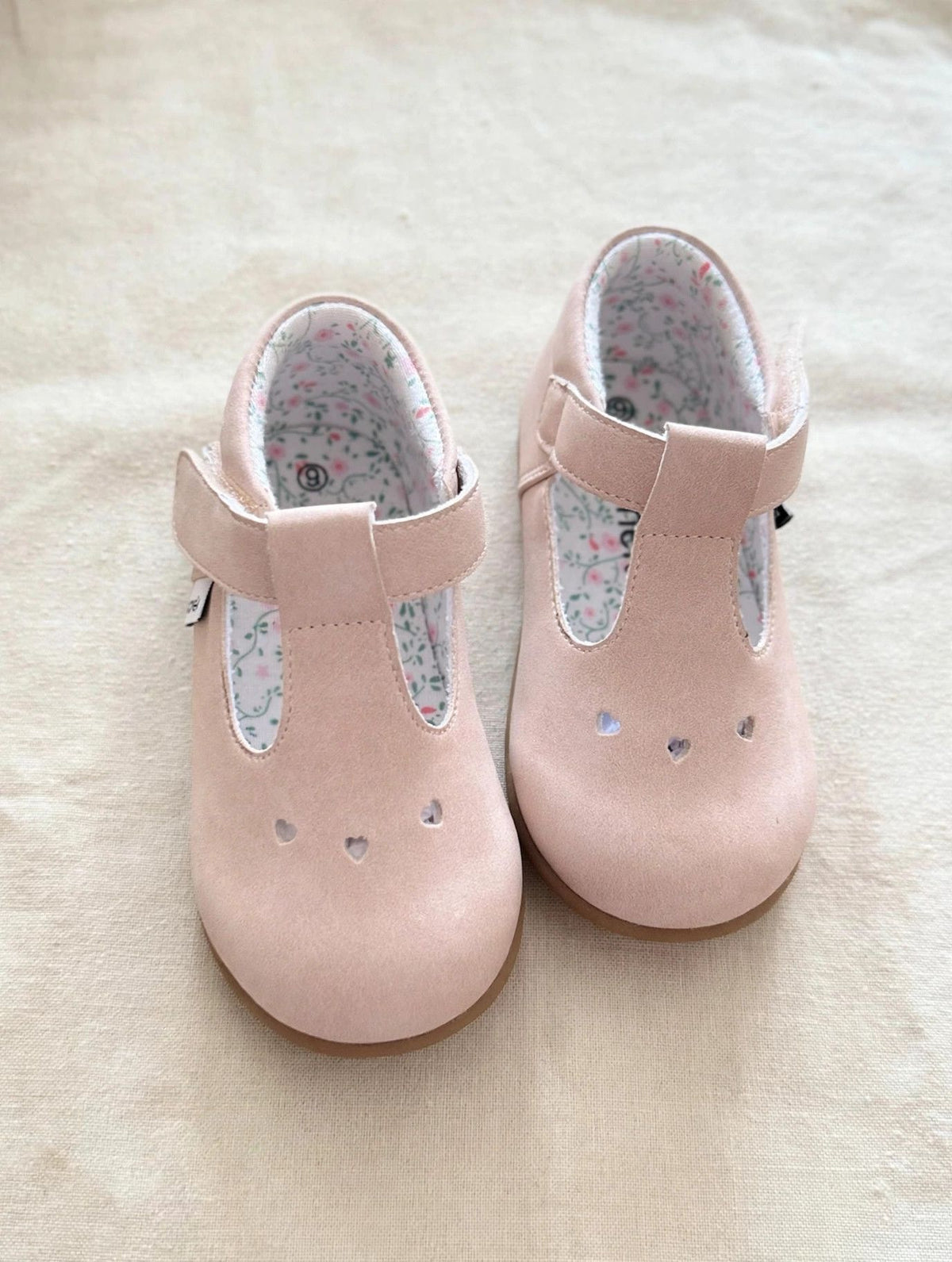 Top view of blush pink kids Mary Jane slip-on shoes with floral-lined openings