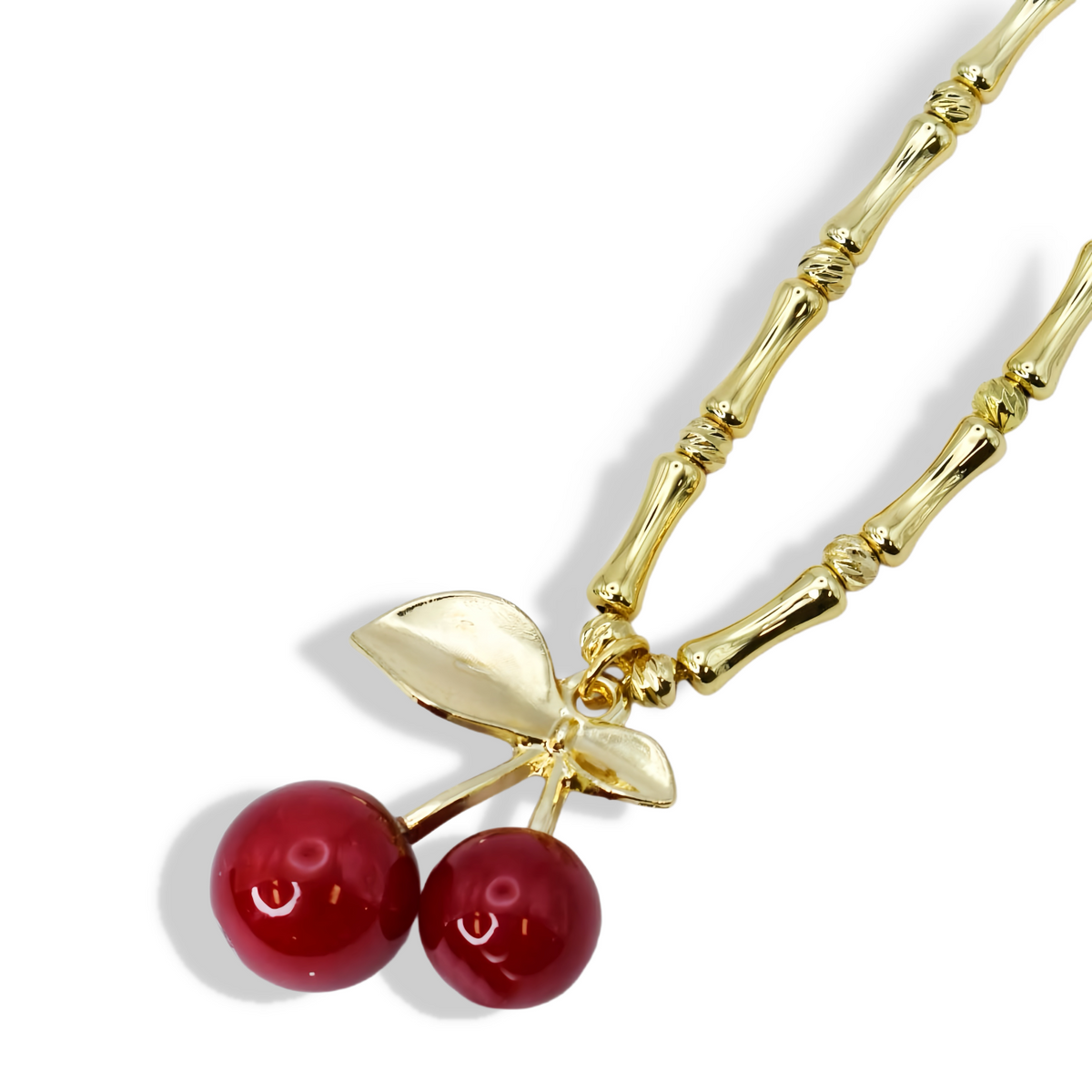 Gold-tone beaded pendant necklace with two red cherry charms and leaf centerpiece