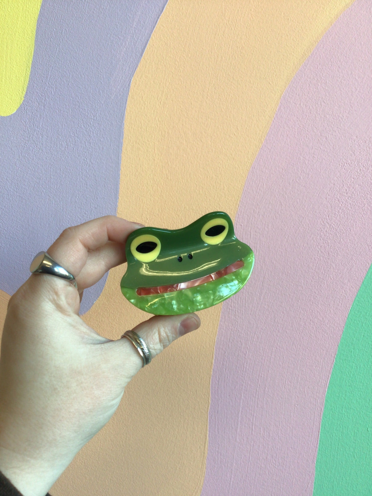 Frog-shaped green hair claw with round eyes and red smiling mouth.