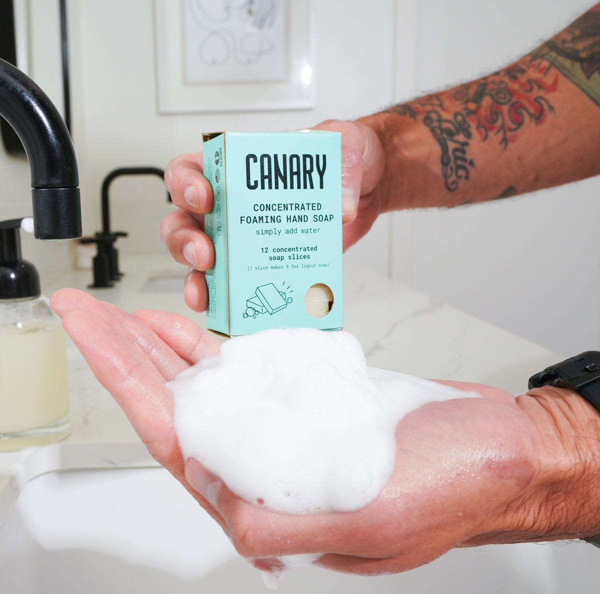 Canary foaming hand soap refill carton held above a hand covered in foam