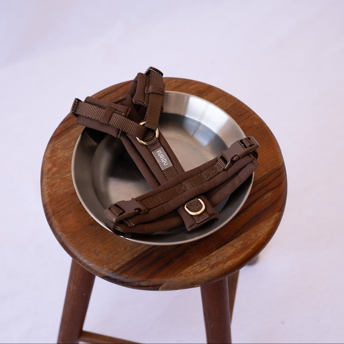 Brown comfort dog harness resting on a wooden chair seat with buckles and straps