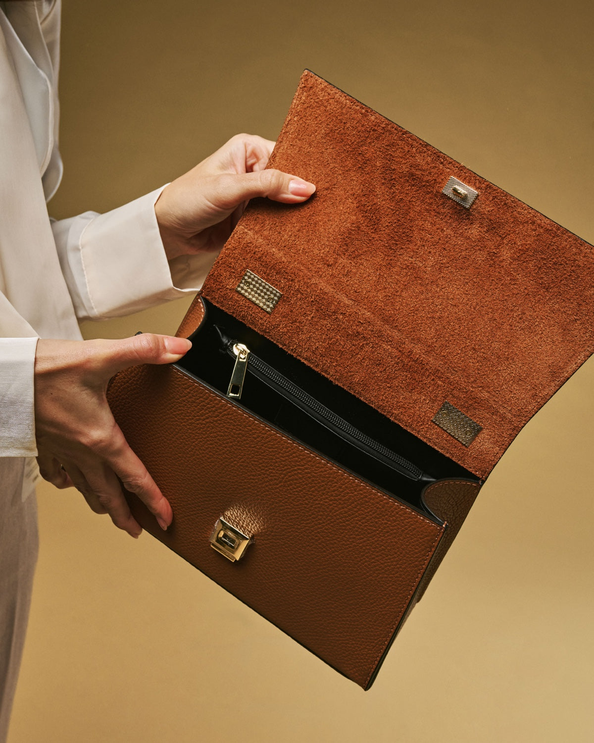 Cognac leather crossbody bag with textured finish and gold clasp hardware, open