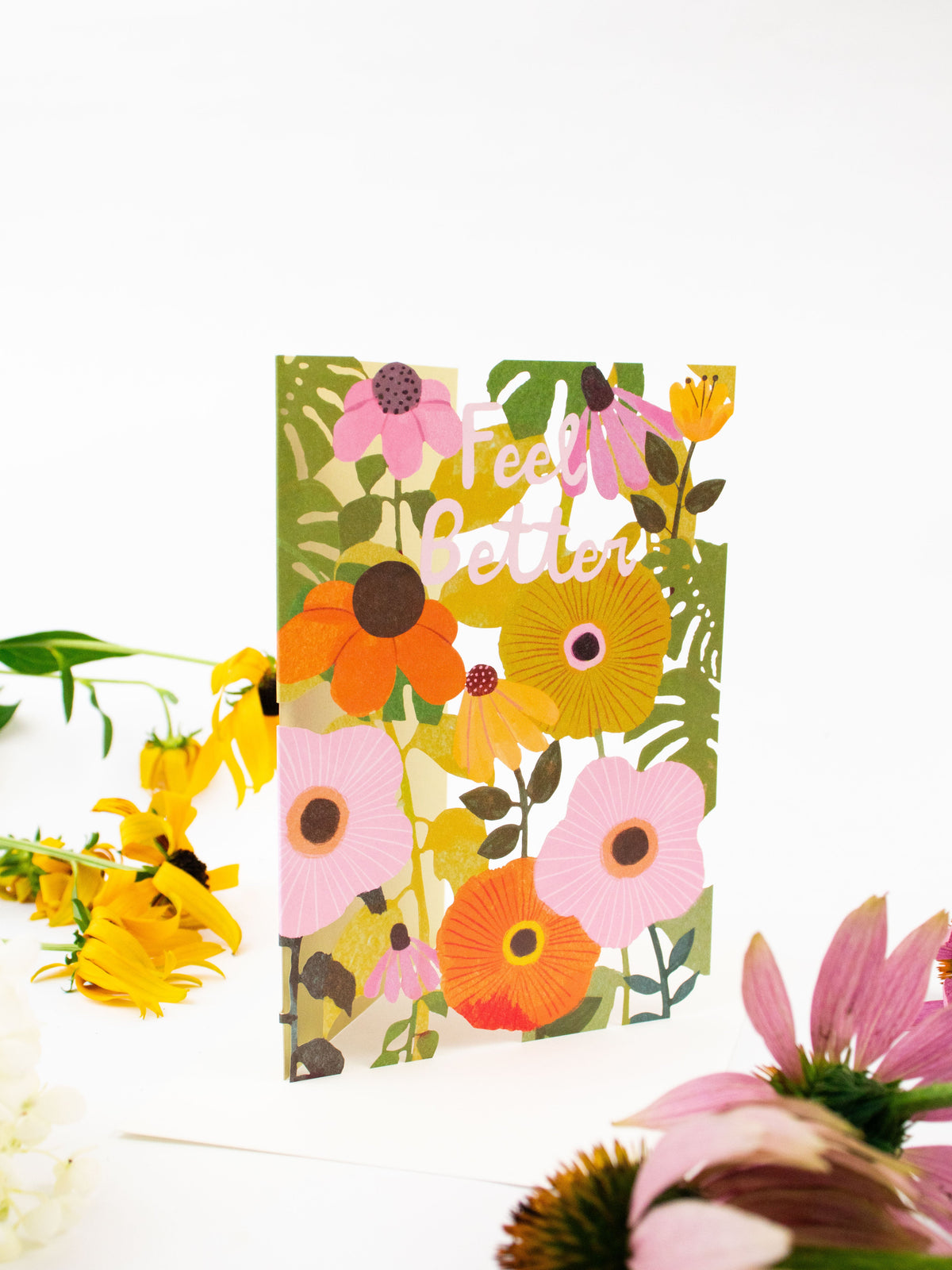 Hand holding floral laser-cut greeting card with “Feel Better” lettering and flower cutouts