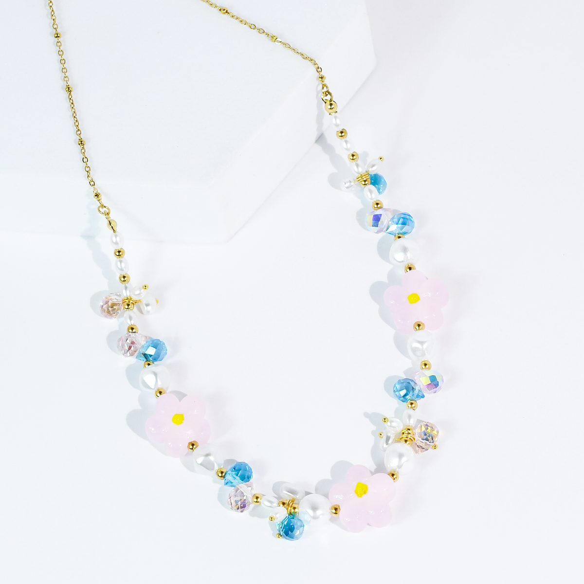Beaded flower necklace with gold chain, pink blossoms, pearl beads, and blue accents