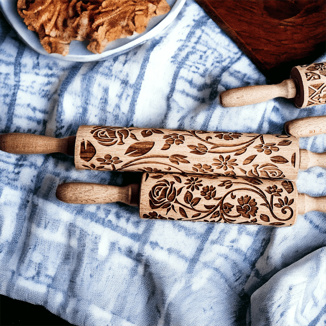 Embossed wood rolling pin with floral carved pattern on light blue fabric