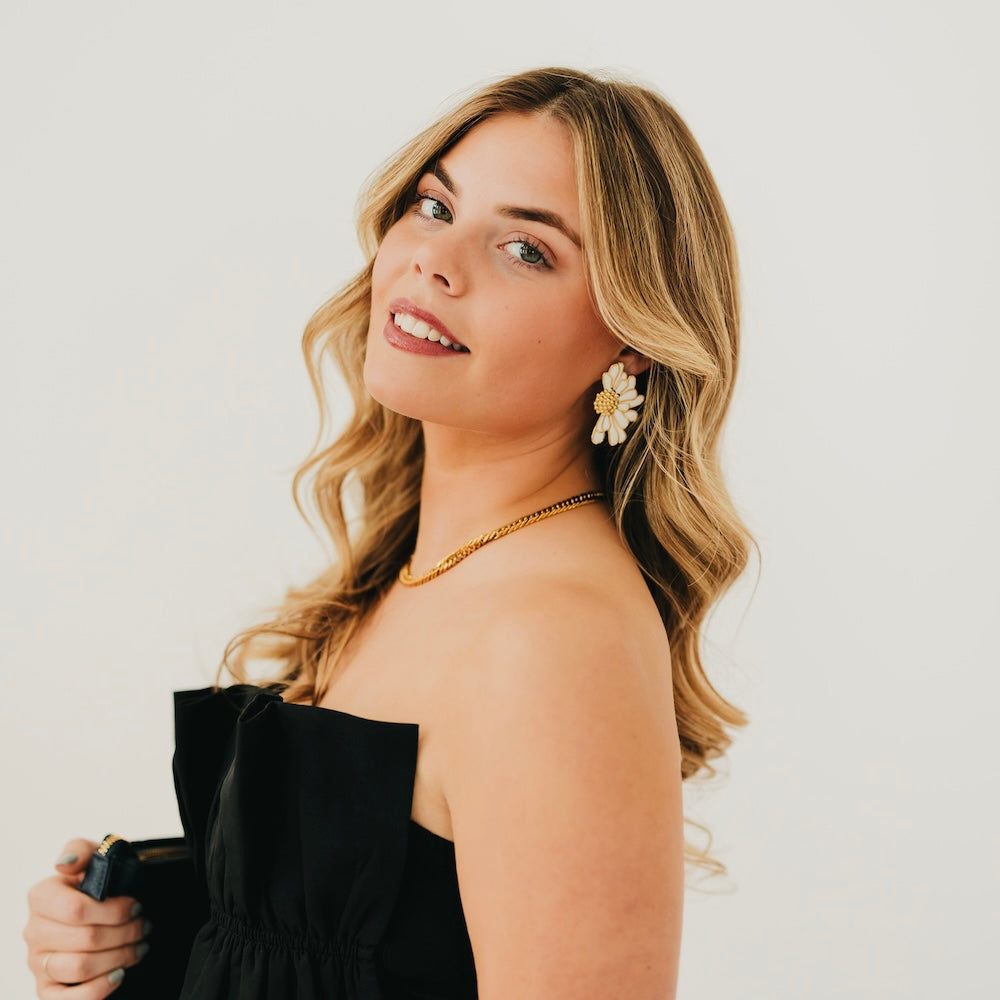 Gold flower stud earrings with white petals, on a model