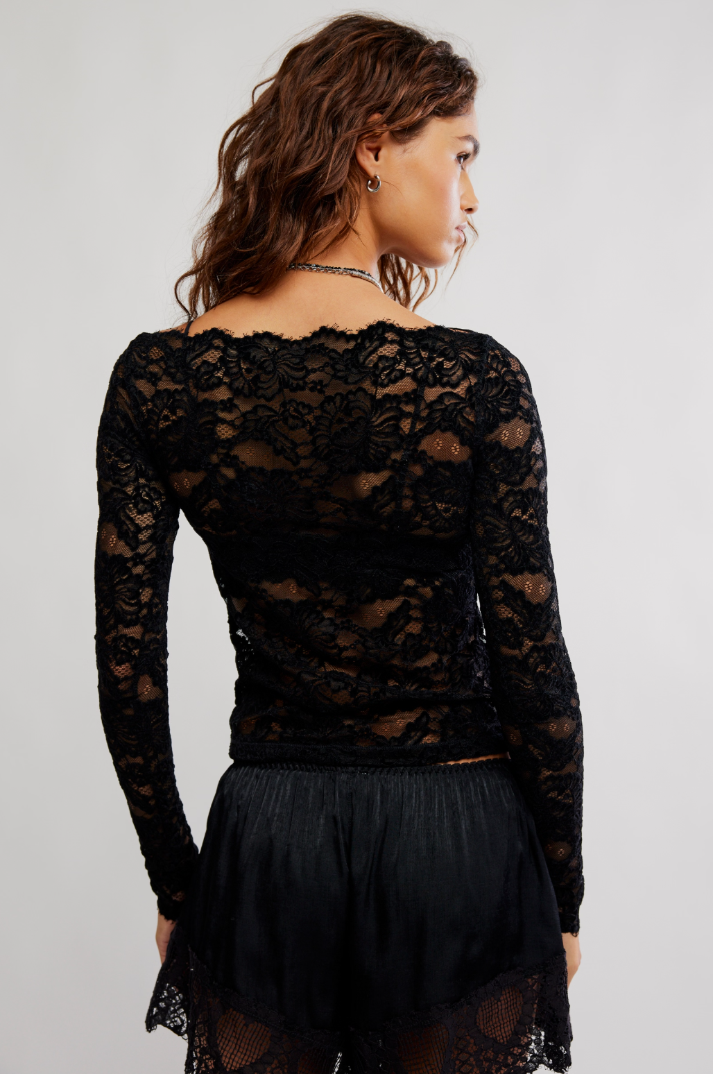 Black lace crop top, back view, long sleeves with scalloped hem