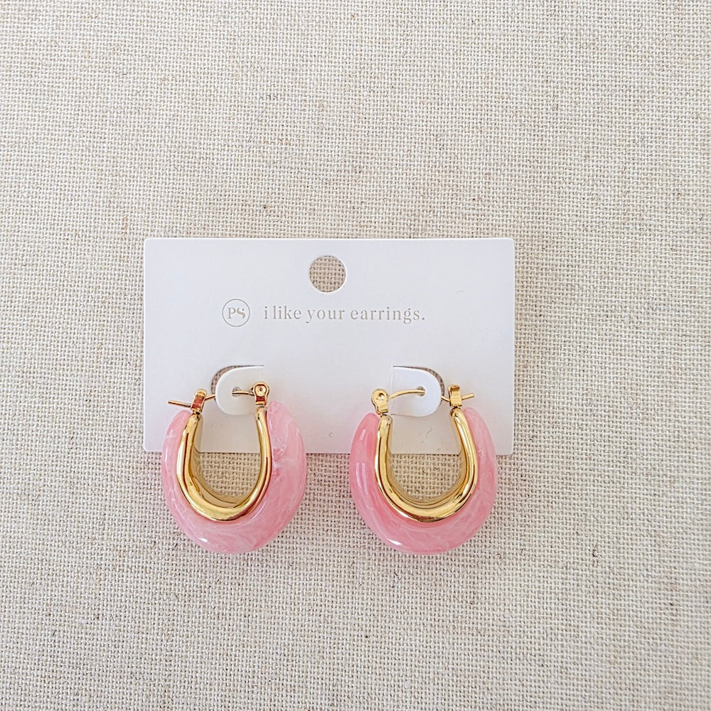Pink resin hoop earrings with gold-tone hinges, shown on retail card