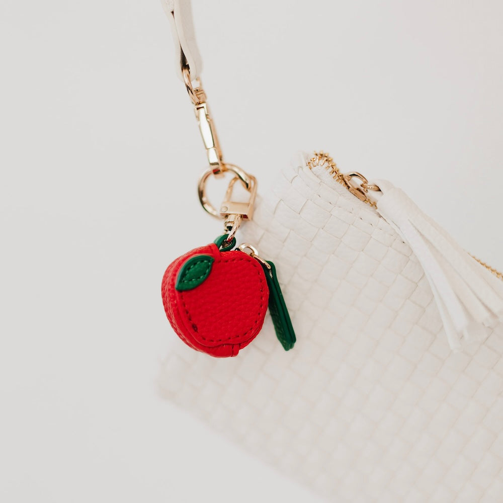 Red fruit leather keychain charm with green cap and small green tassel.