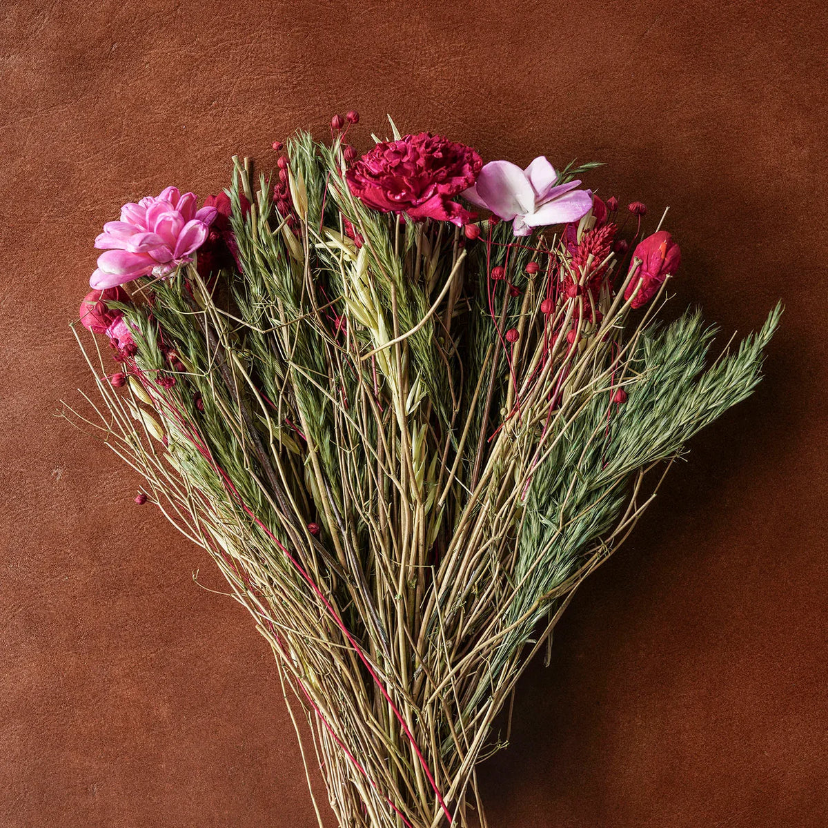 Heart-shaped dried floral and grass bouquet with pink and deep magenta flowers