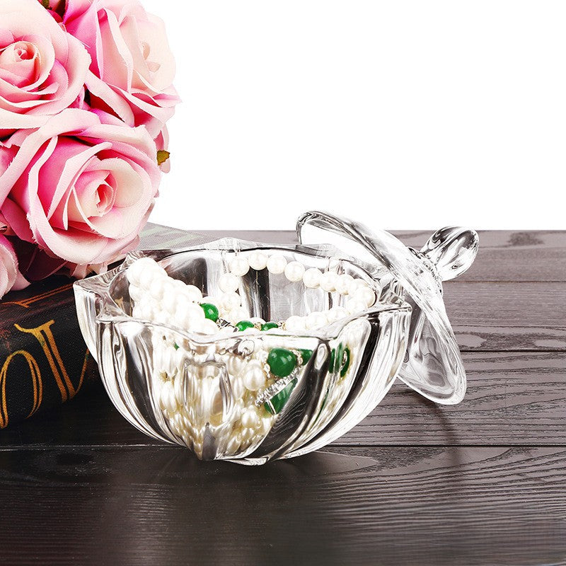 Open cut-glass jar filled with bead jewelry, with its lid resting beside it