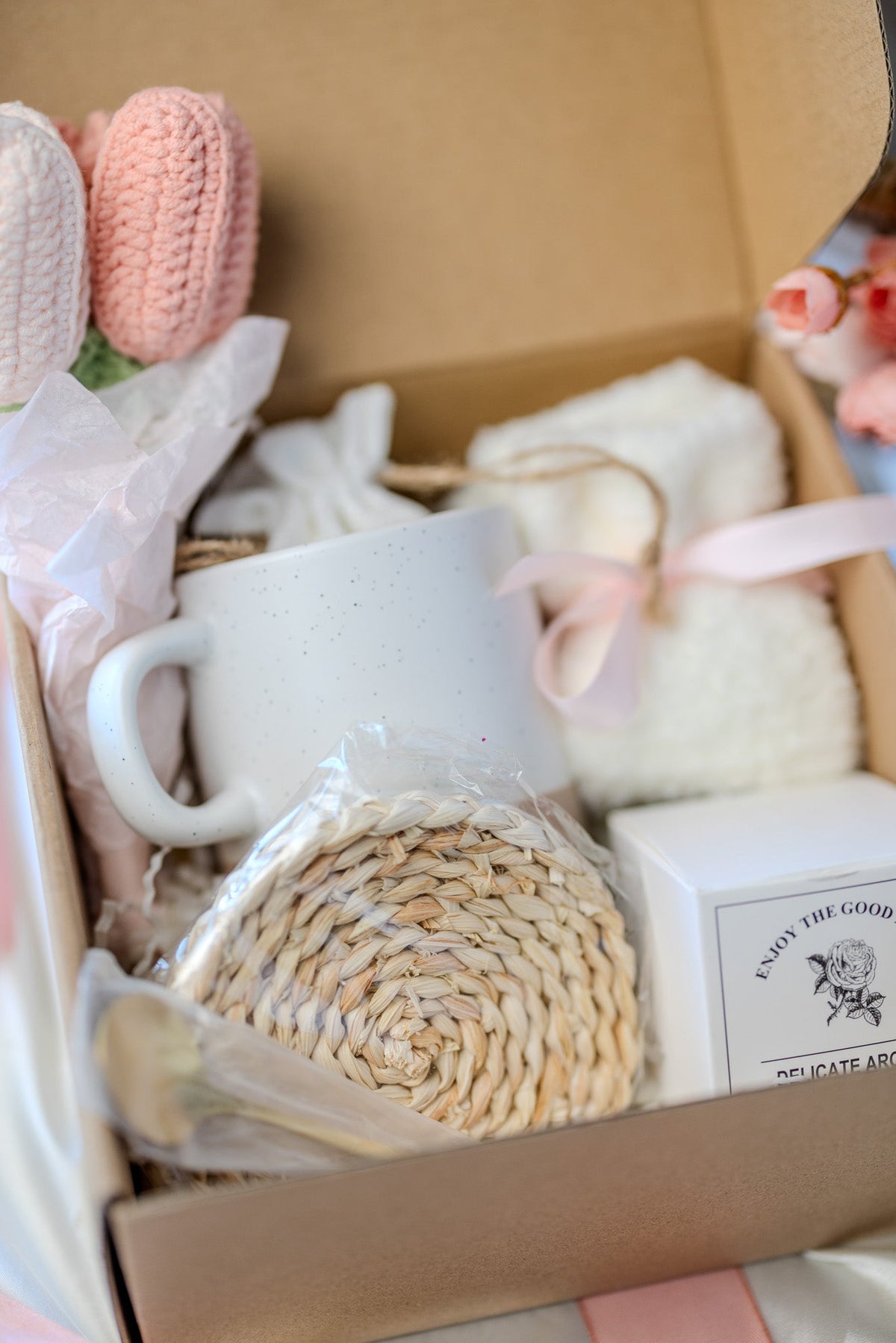 Self-care gift box with white ceramic mug, cream scrub, crocheted round sponge, and soaps