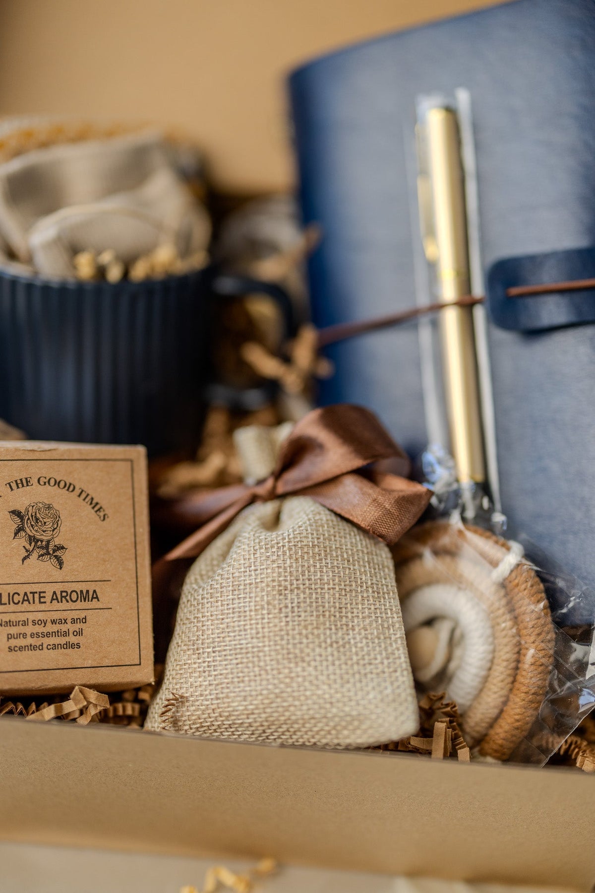 Gift box detail showing navy mug, beige pouch, and blue notebook with gold pen