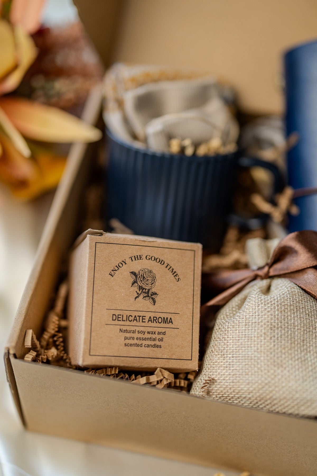 Gift box detail featuring delicate aroma candle box, navy mug, and beige pouch