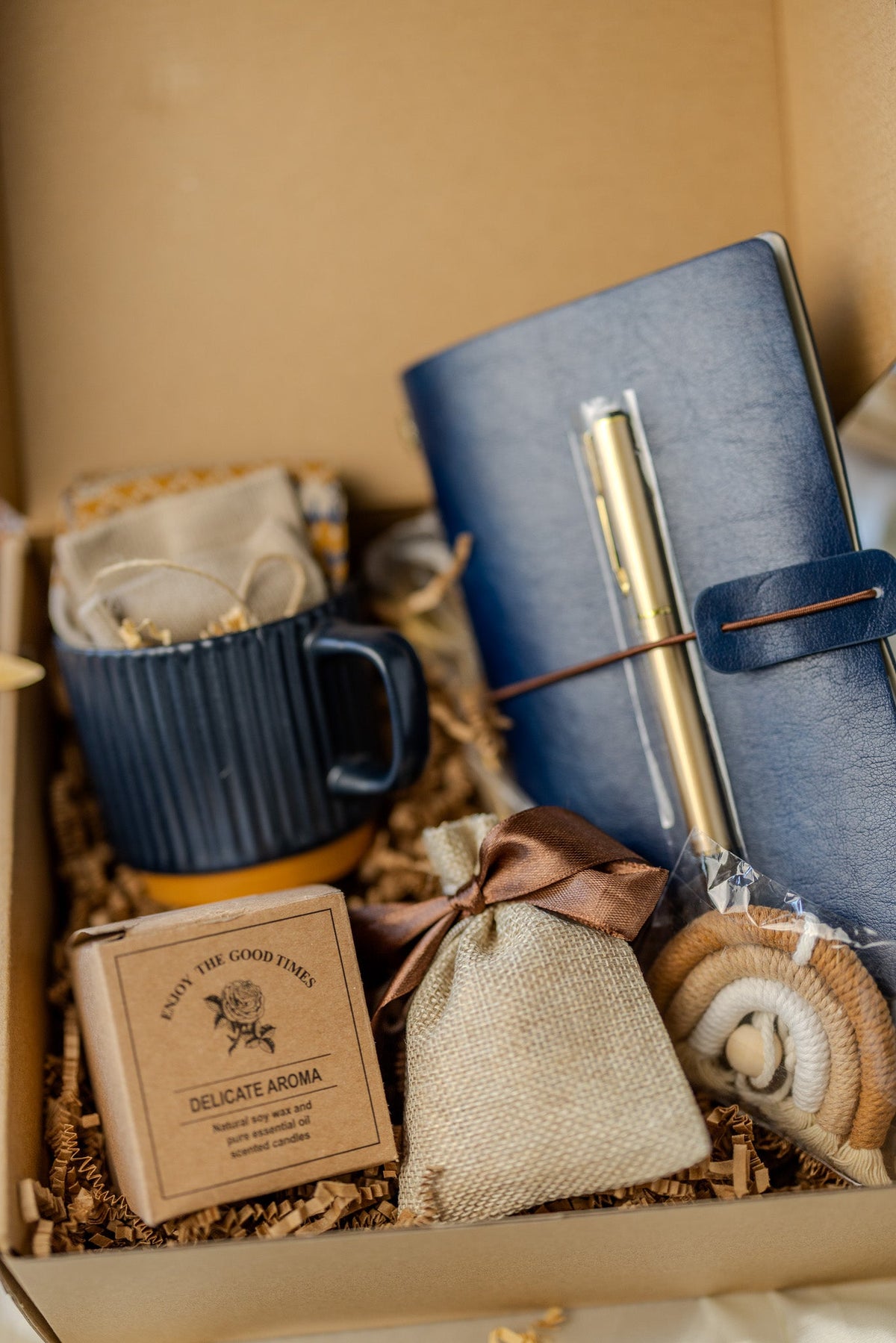 Gift box with blue notebook, gold pen, navy mug, and small fabric pouch inside