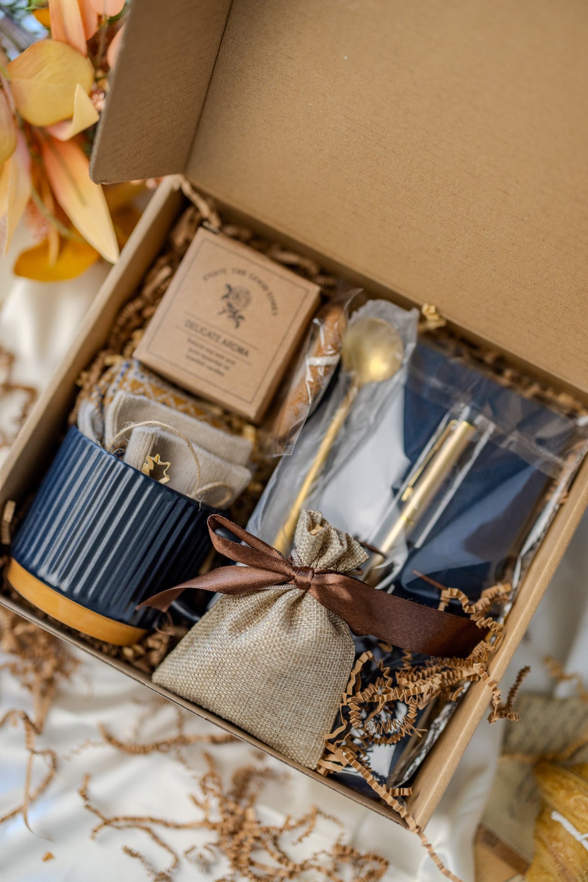 Gift box with blue notebook, navy mug, beige pouch, and small packaged items