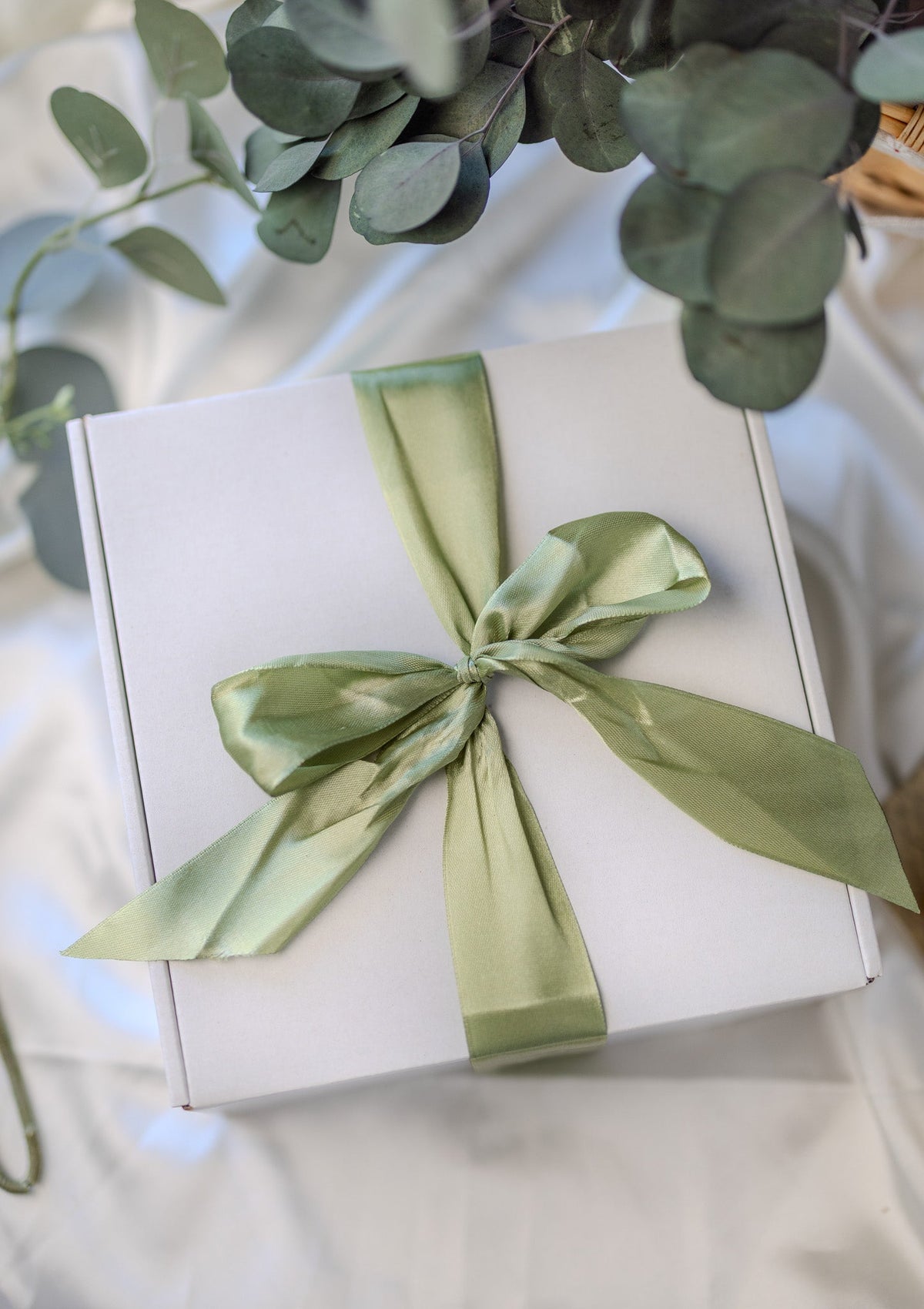 White gift box with sage green satin ribbon bow on top