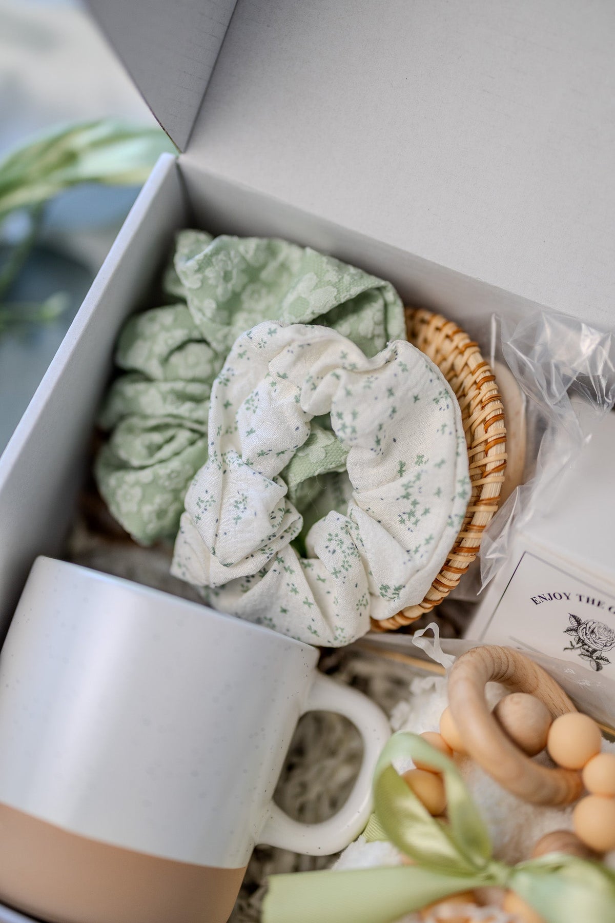 Self-care gift box with white mug, green scrunchie, woven sponge, and bead soap