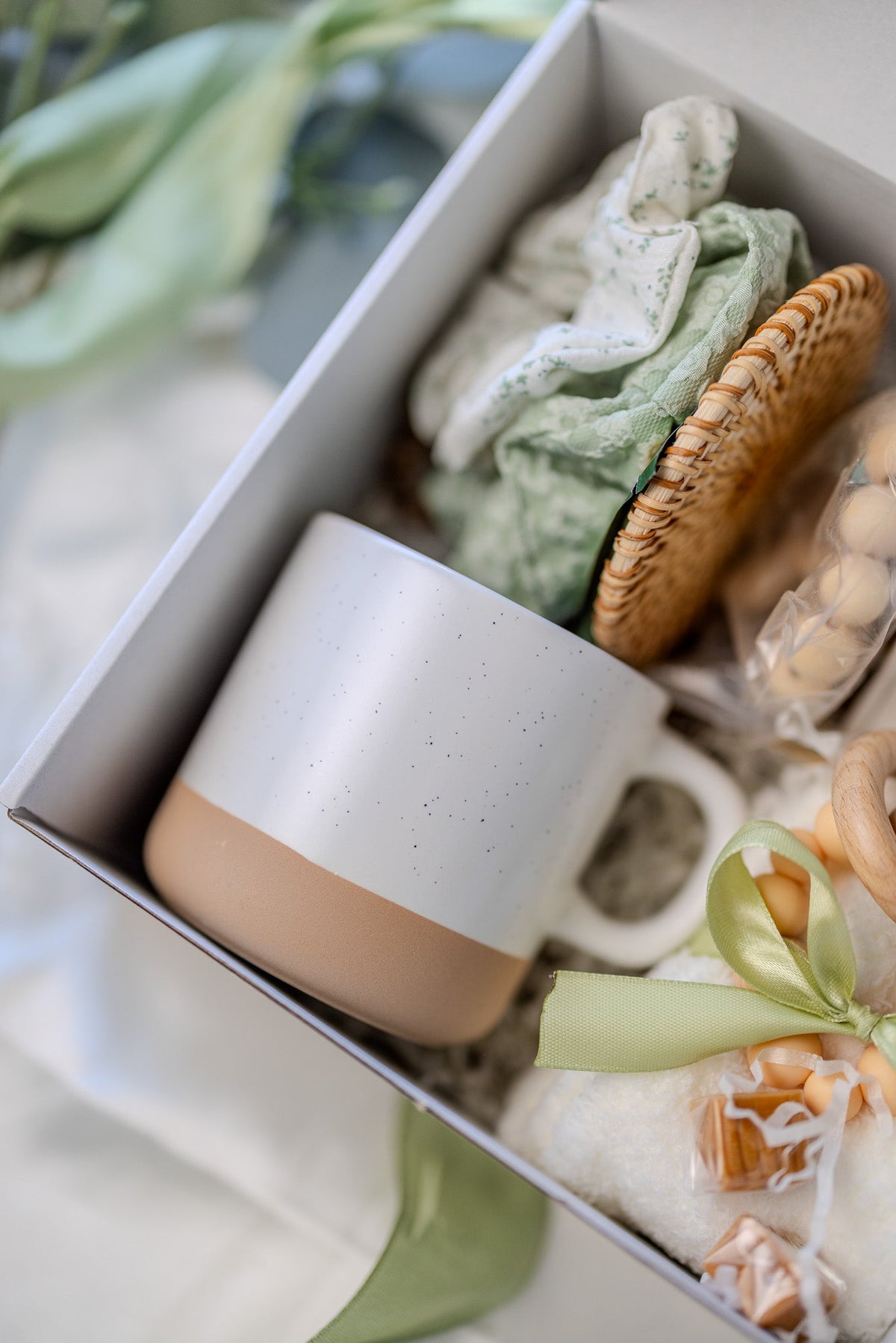 Self-care gift box with white mug, patterned soap, woven sponge, and ribbon bow